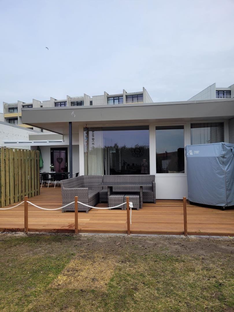 Deck with seating, wooden surface, and covered hot tub.