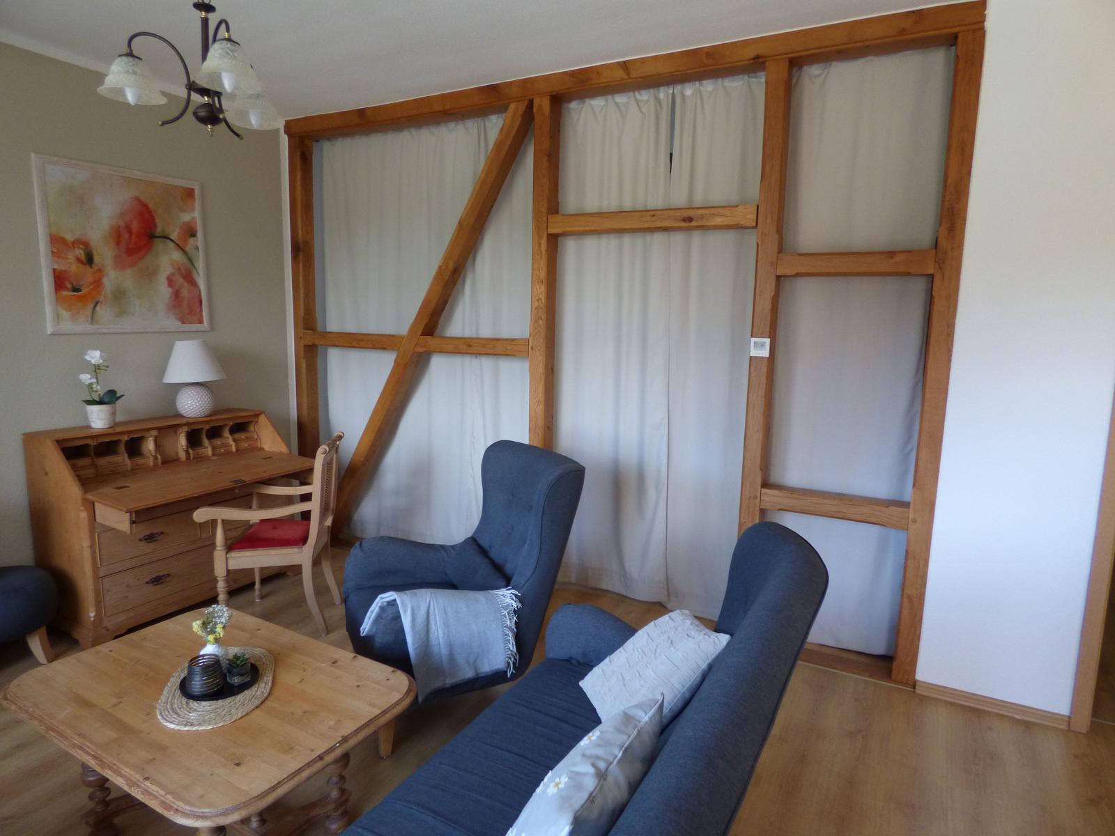Wohnzimmer mit Holzrahmen, Sofa, Sessel und Schreibtisch.