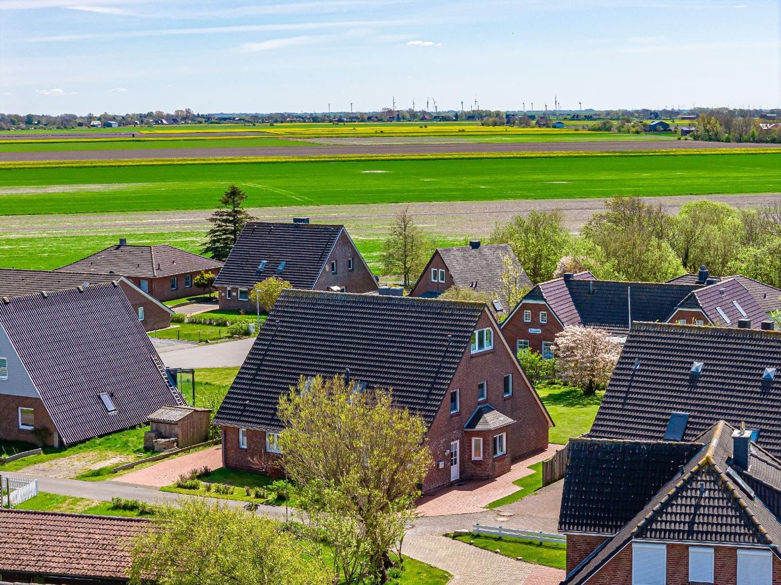 Dorf mit roten Häusern und grünen Feldern unter blauem Himmel.