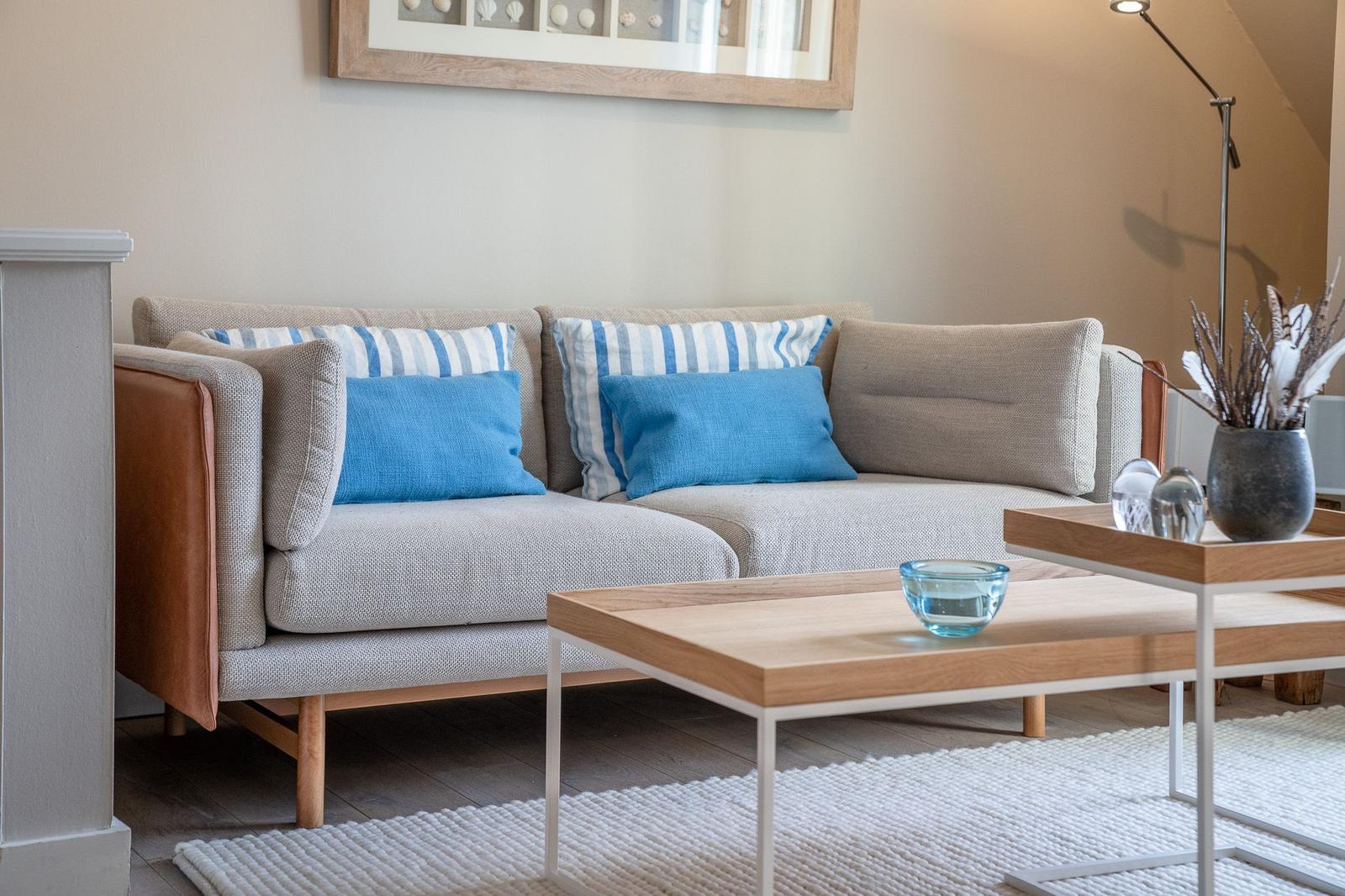 Ein Sofa mit blauen Kissen und einem Holztisch im Wohnzimmer.