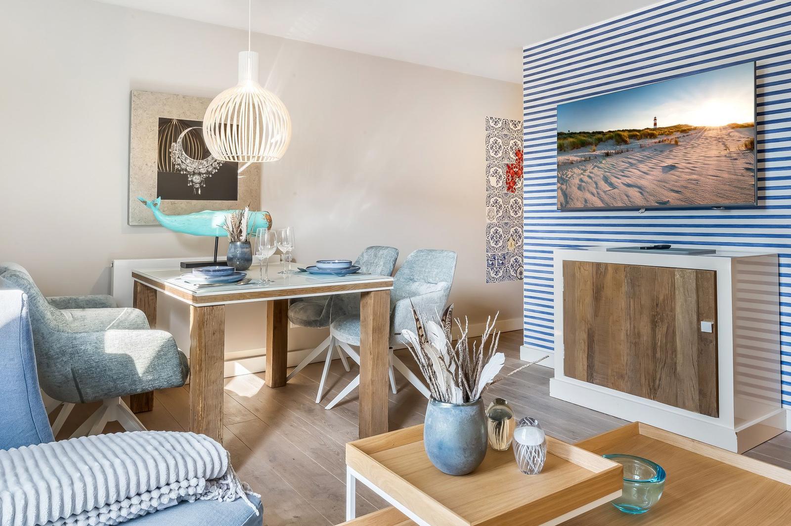 Esszimmer mit Holztisch, Stühlen und Wandbild. Fernseher an gestreifter Wand.