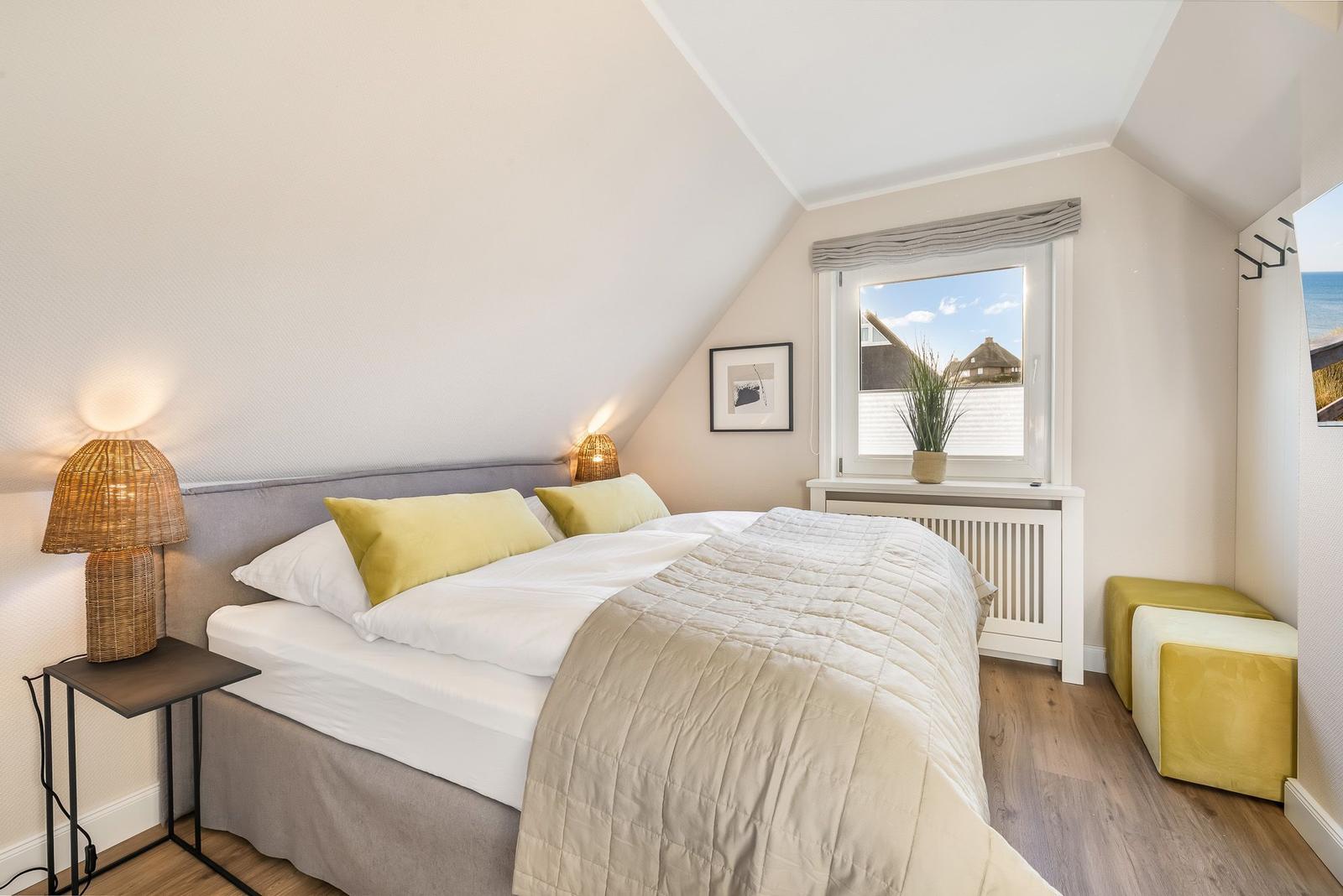 Schlafzimmer mit Dachschräge, Bett, Nachttisch und Fenster mit Blick.