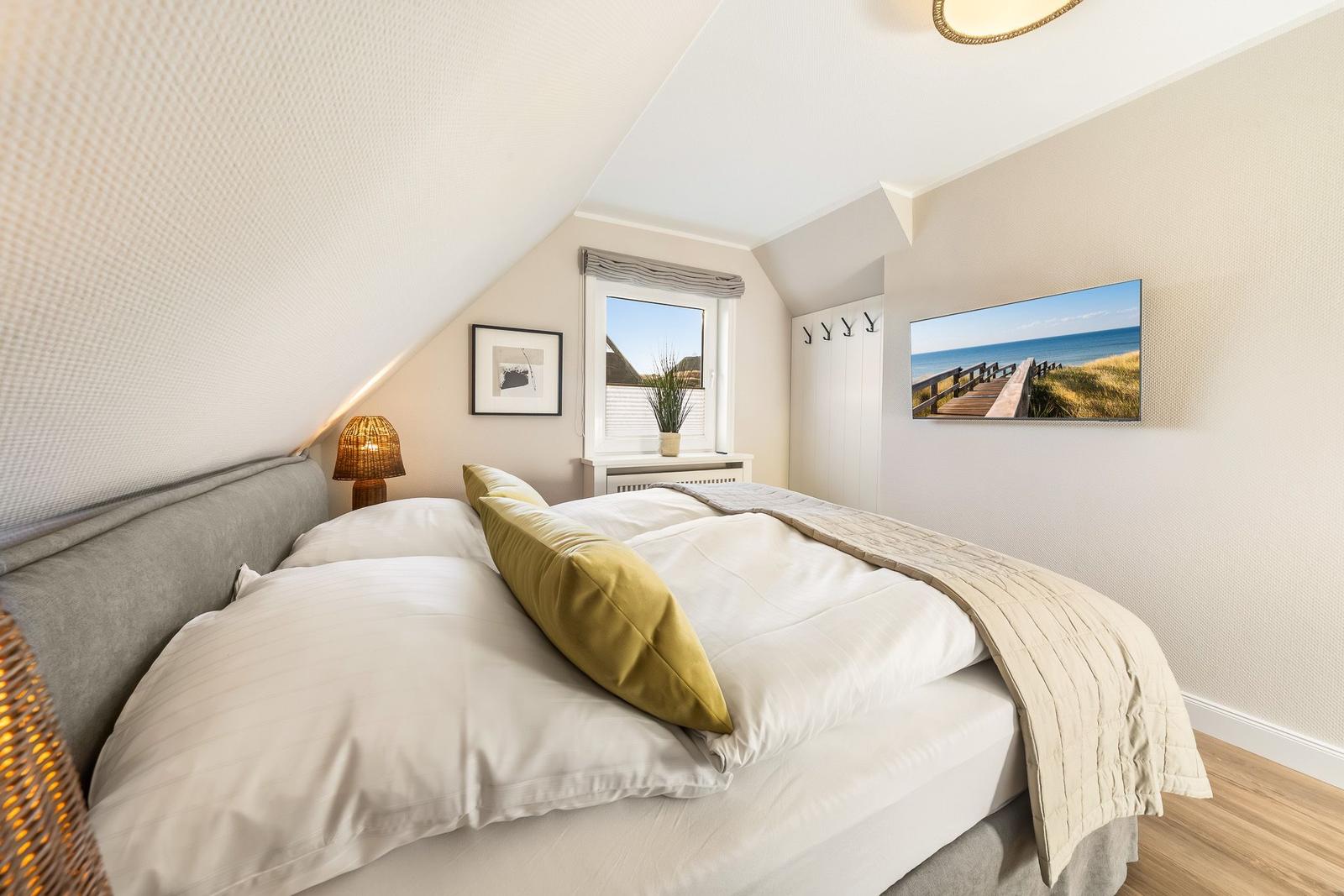 Schlafzimmer mit Dachschräge, Bett, Fenster und Wandbild
