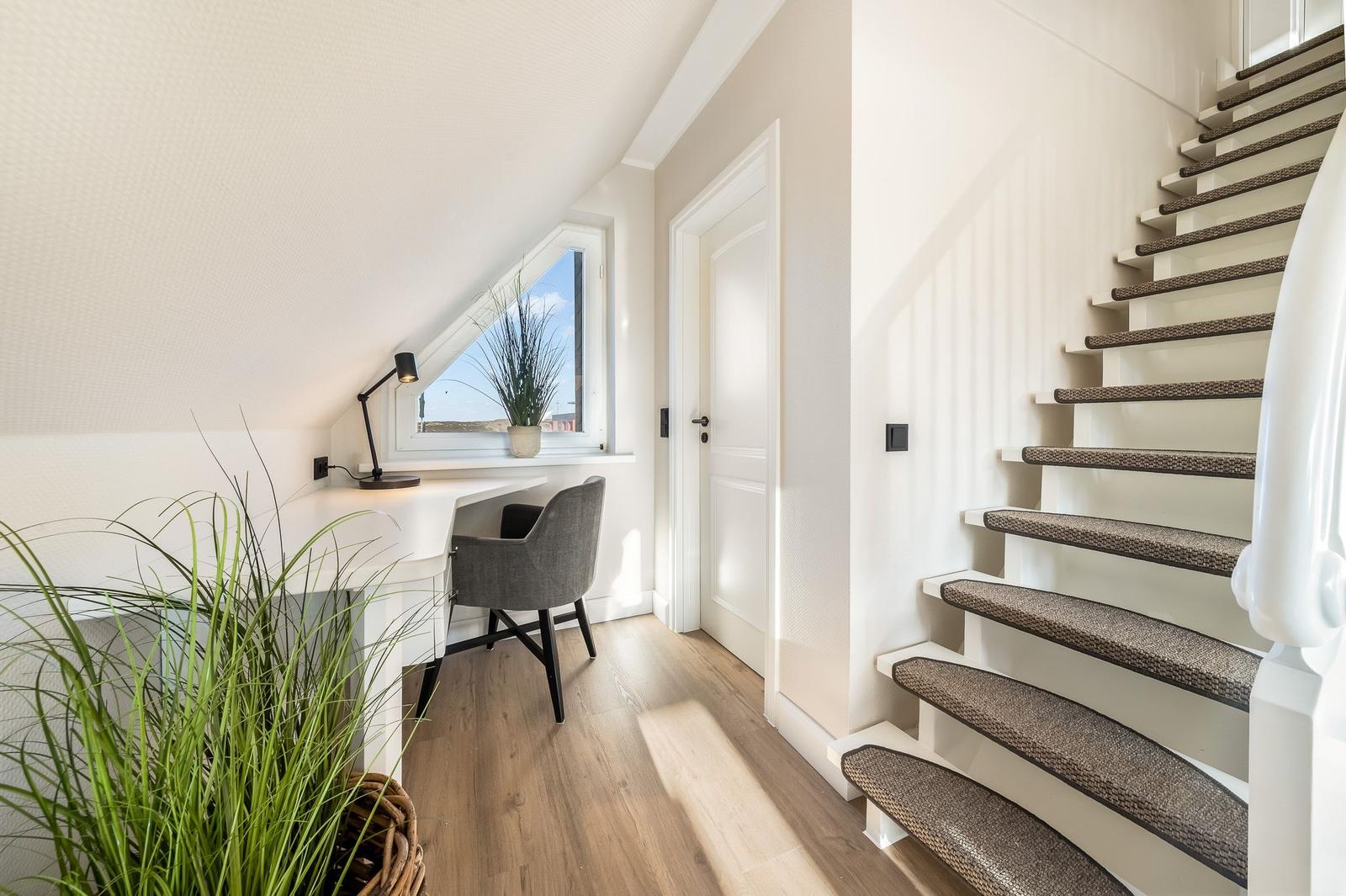 Höhenlage mit Schreibtisch, Pflanzen und Treppe zur oberen Etage.