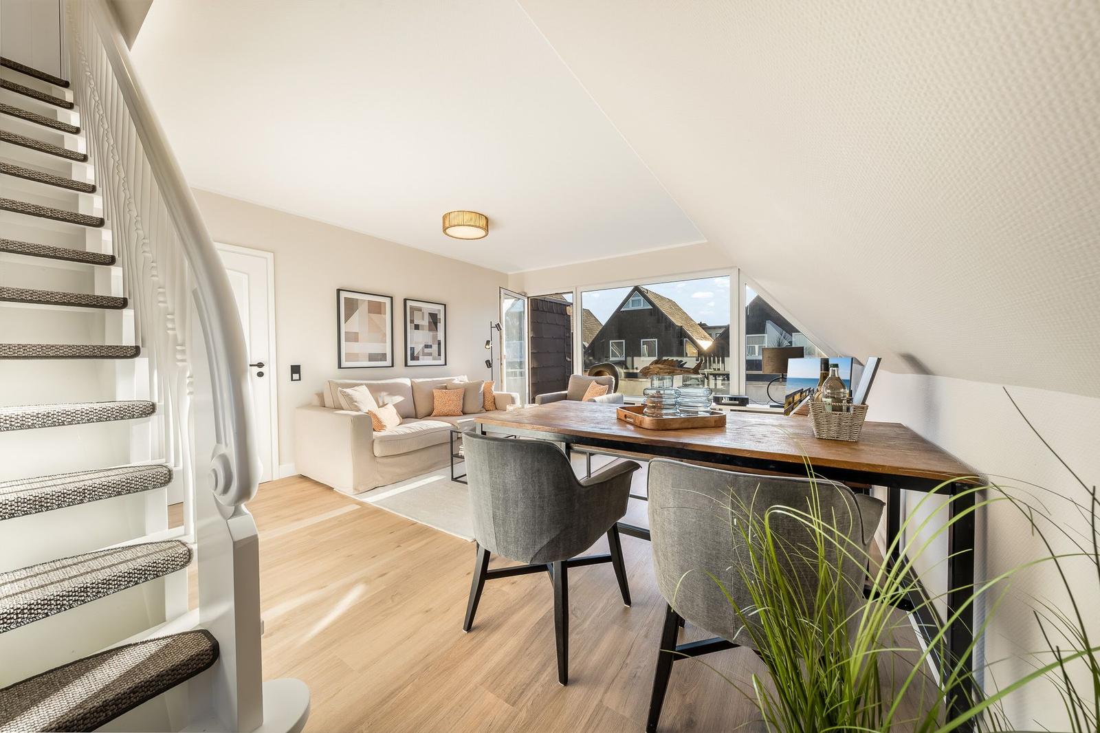 Wohn- und Essbereich mit Treppe und großem Fenster. Holzboden und moderne Möbel.