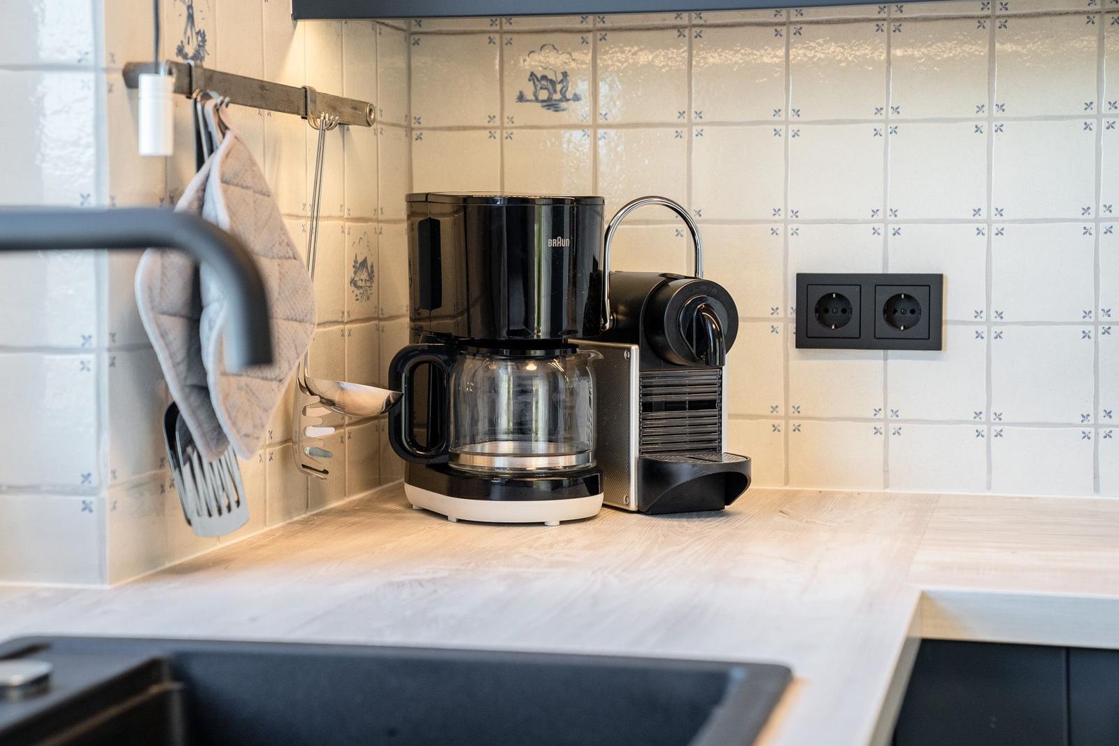 Küchenzeile mit Kaffeemaschine und Kaffeemaschine auf Holzoberfläche.