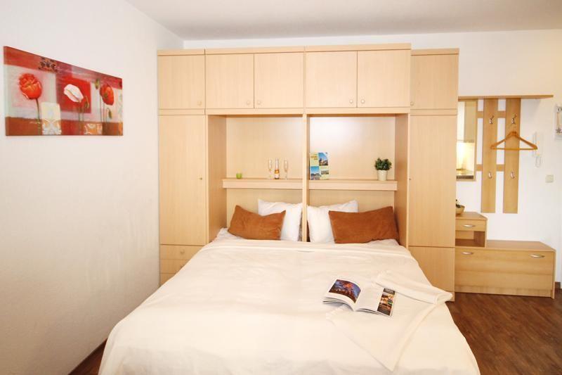 Schlafzimmer mit Bett, Holzmöbel und Wandbild mit roten Blumen.