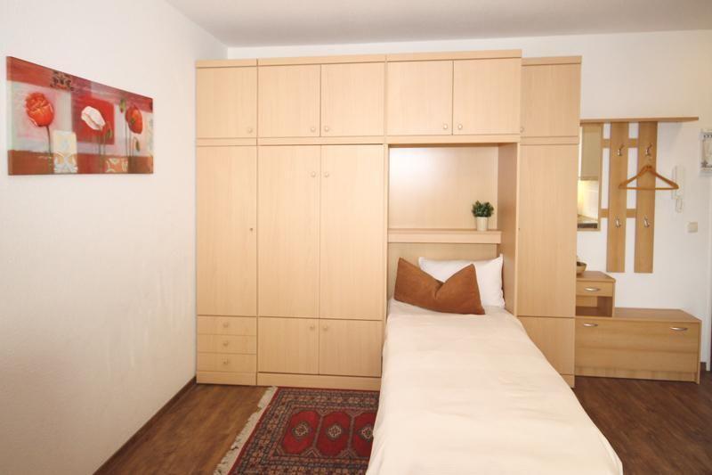 Schlafzimmer mit Bett, Kleiderschrank und Teppich