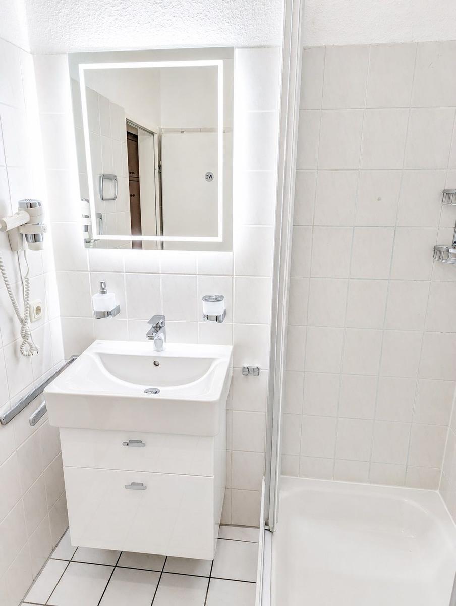 Badezimmer mit Waschbecken, Spiegel und Dusche