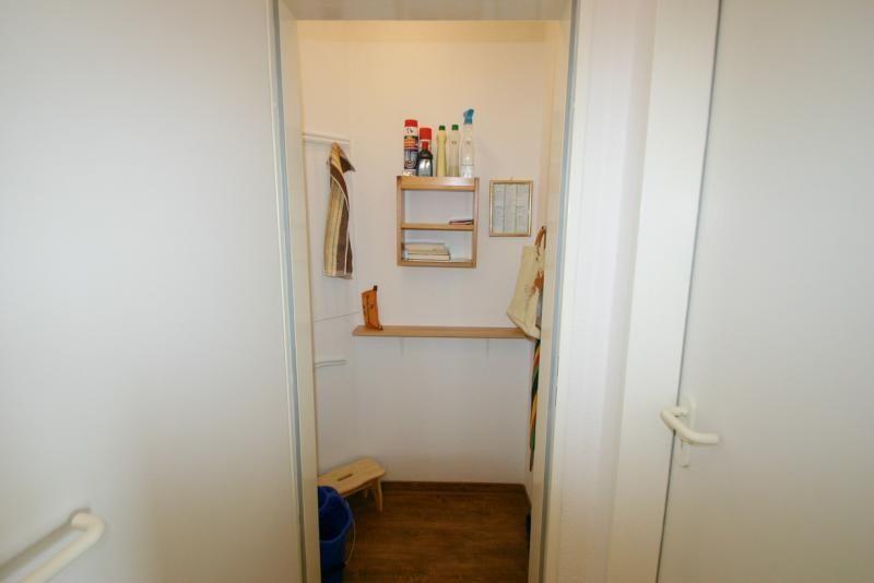 Durchgang mit kleinem Regal, Handtuch und Reinigungsmitteln an der Wand.