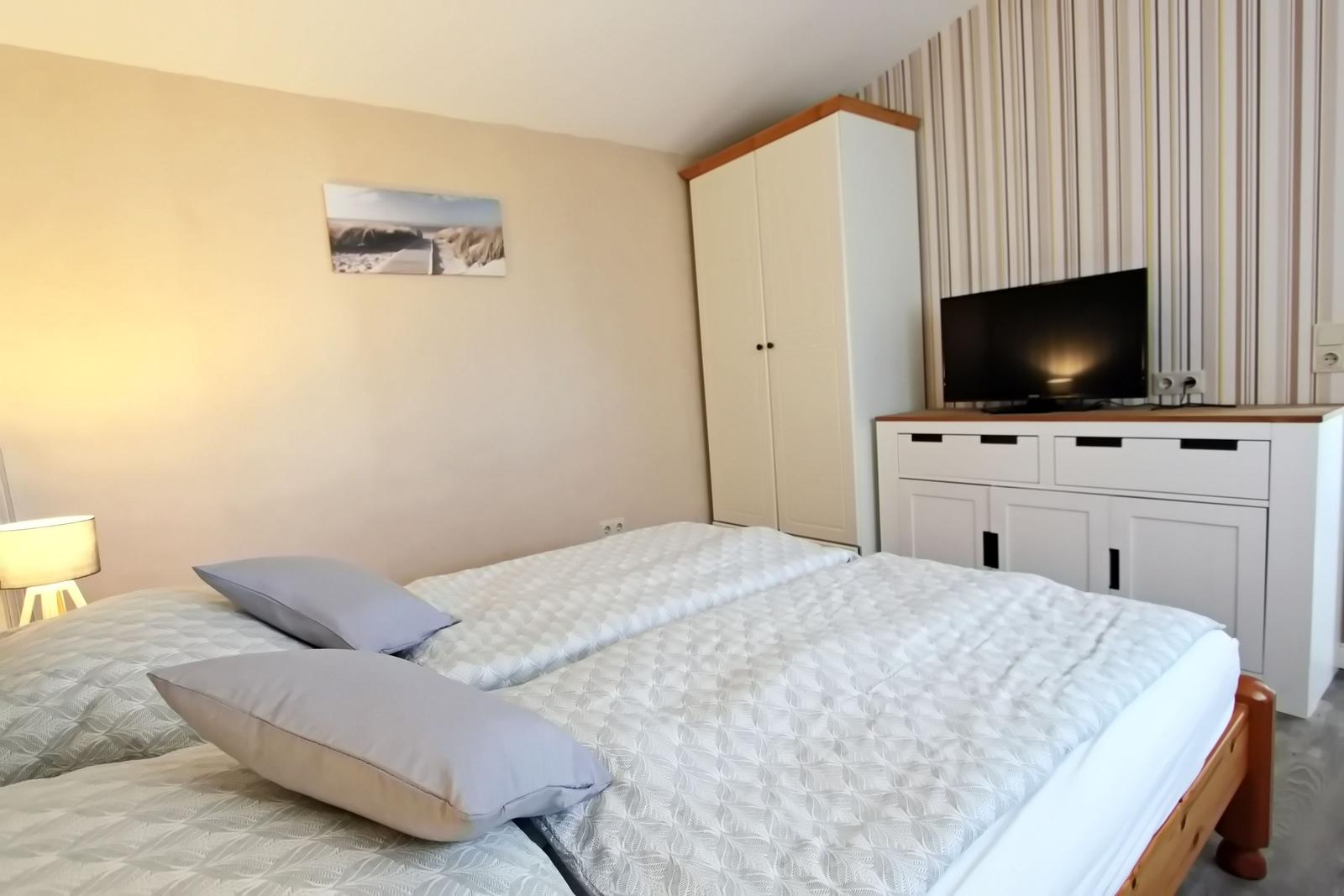 Schlafzimmer mit Doppelbett, Kleiderschrank und TV-Möbel.