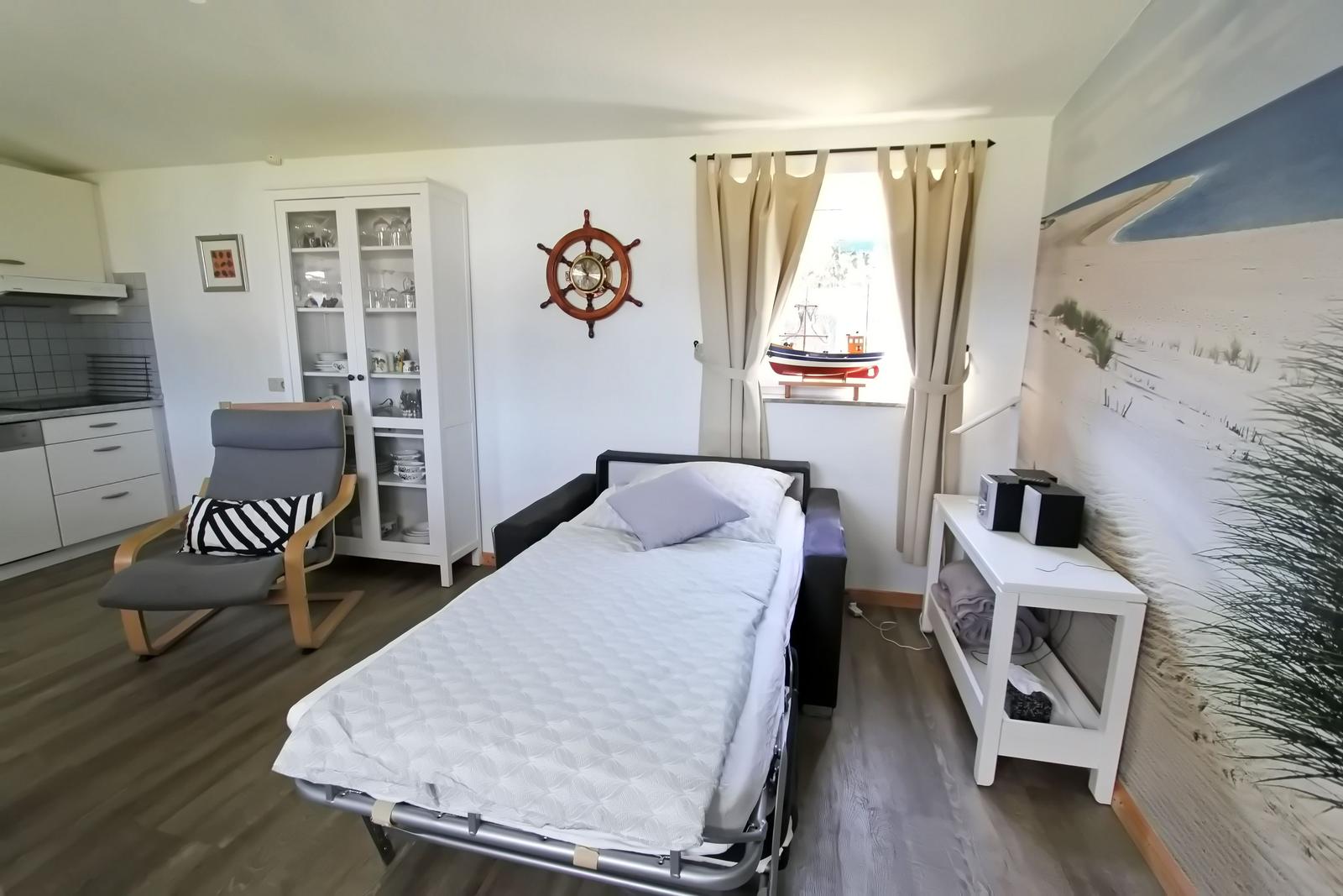 Schlafzimmer mit Bett, Küchenbereich und Wandbild