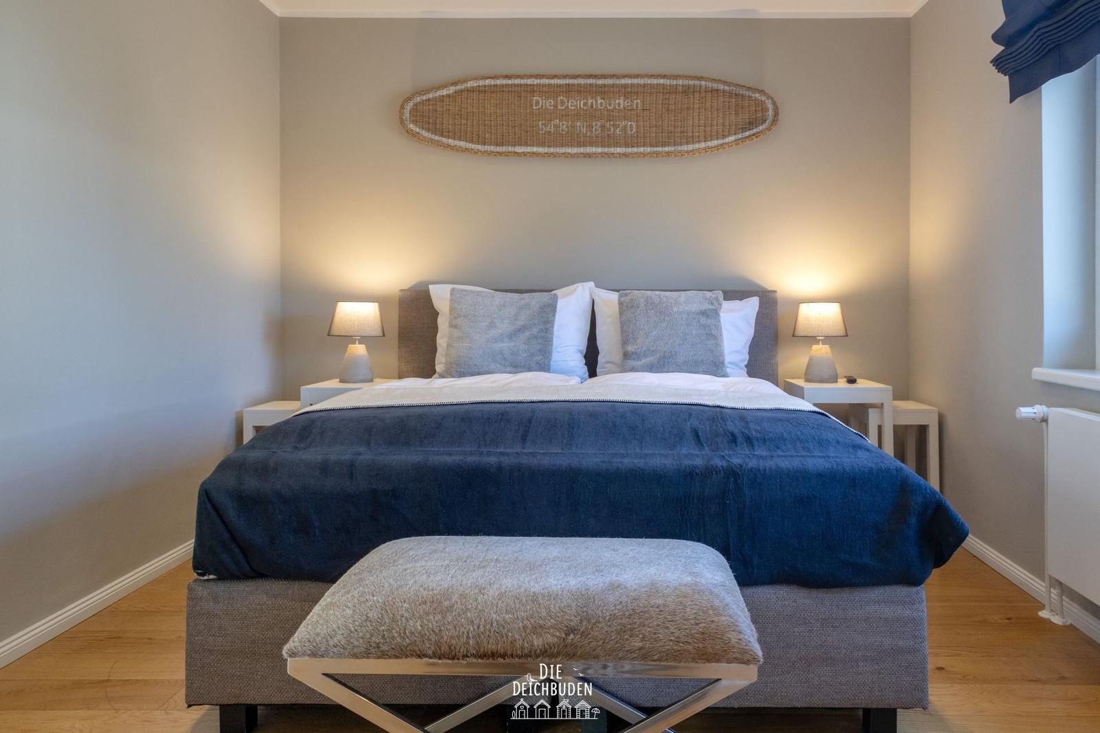 Schlafzimmer mit Bett, Nachttischen und Wanddekoration.