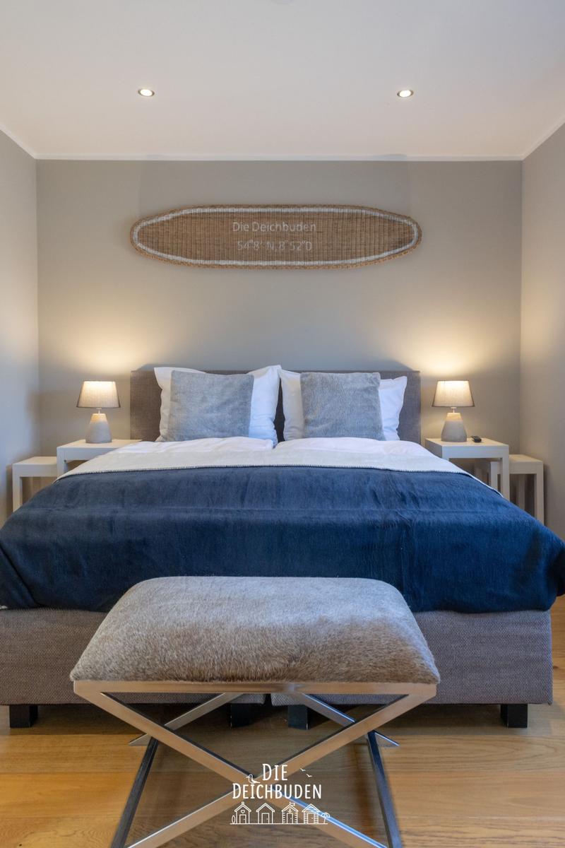 Schlafzimmer mit Bett, Nachttischen und Wanddekoration.