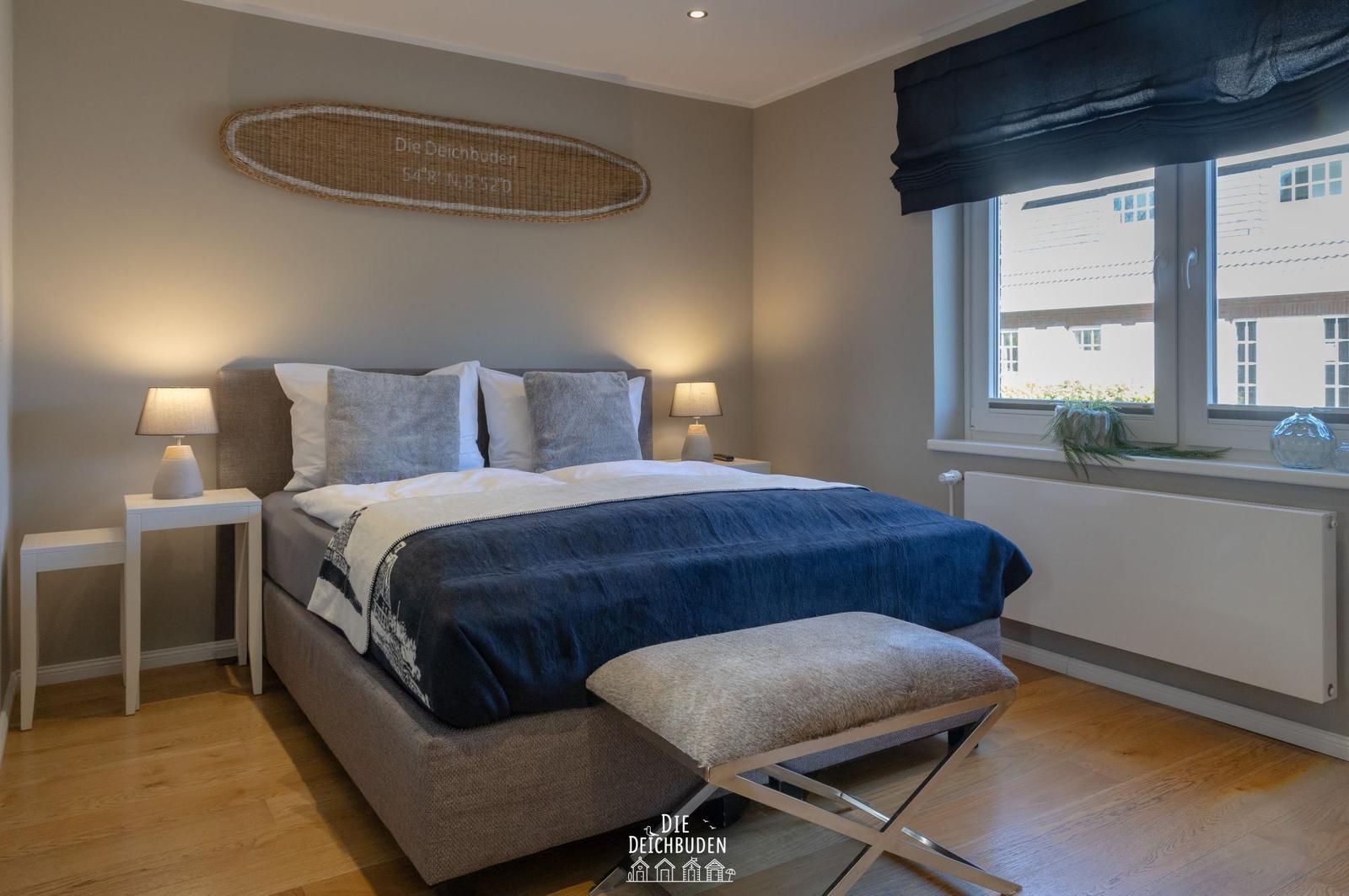 Schlafzimmer mit Bett, Nachttischen und Fenster. Wanddekoration mit Koordinaten.