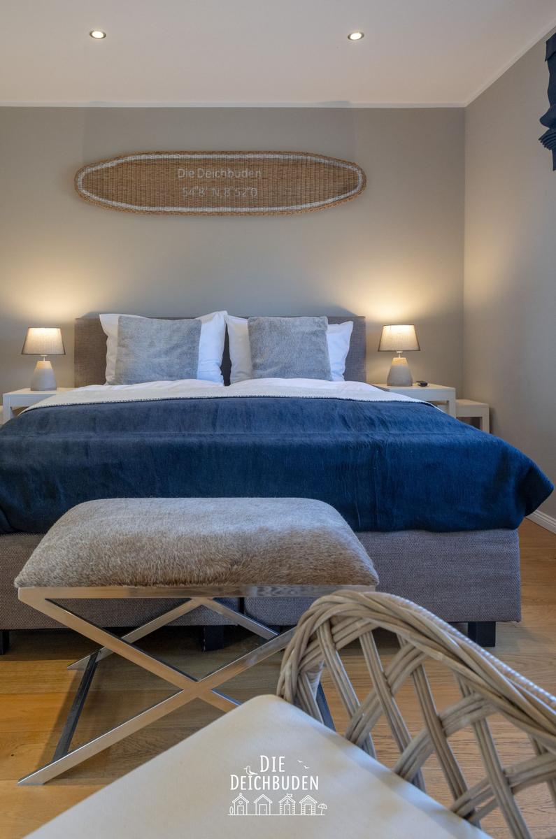 Schlafzimmer mit Bett, Nachttischen und Wanddekoration.