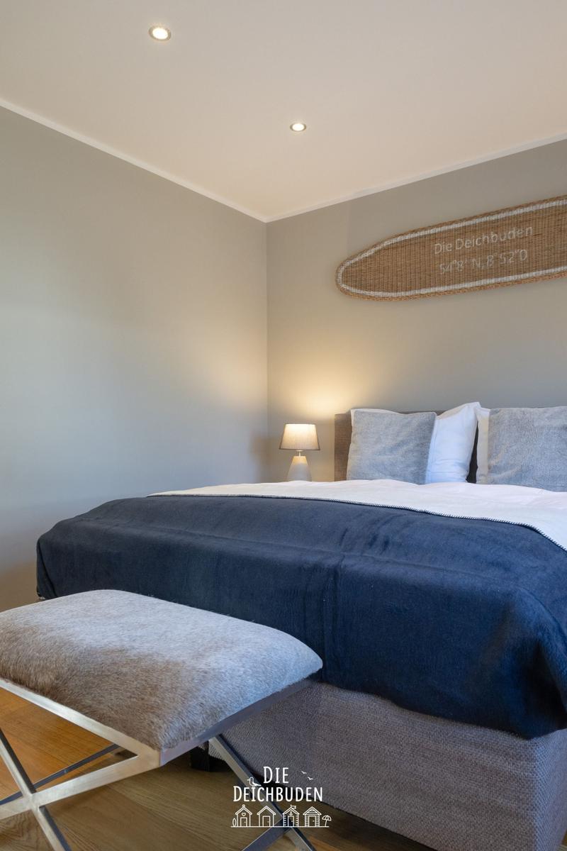 Schlafzimmer mit Bett, Nachttisch und Wanddekoration.