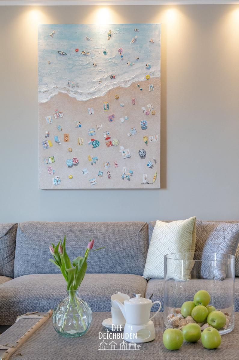 Ein Sofa mit Kissen, eine Vase mit Tulpen und ein Bild an der Wand.