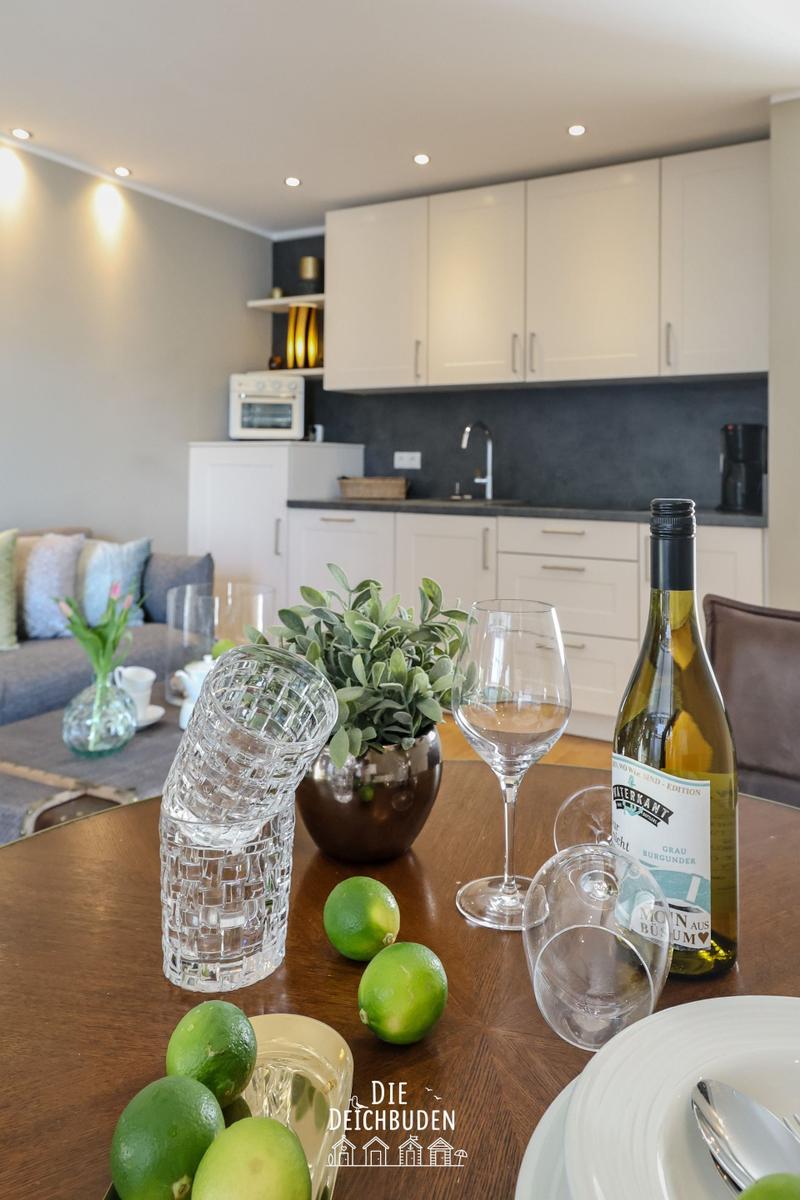 Esstisch mit Wein, Zitronen und Pflanze vor Küchenbereich