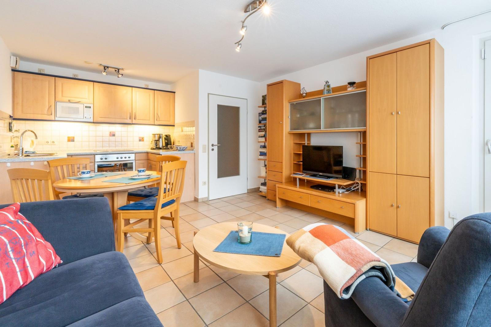 Wohnung mit Küche, Essbereich und Wohnzimmer mit Fernseher und Holzmöbeln.