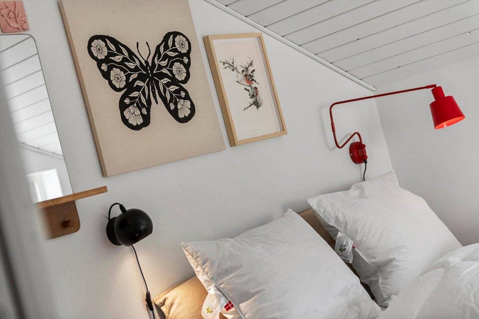 Schlafzimmer mit Bett, Wandlampen und Kunst an der Wand.