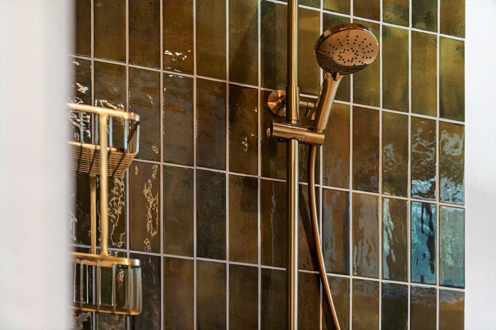 Dusche mit goldfarbenem Duschsystem und farbigen Fliesen