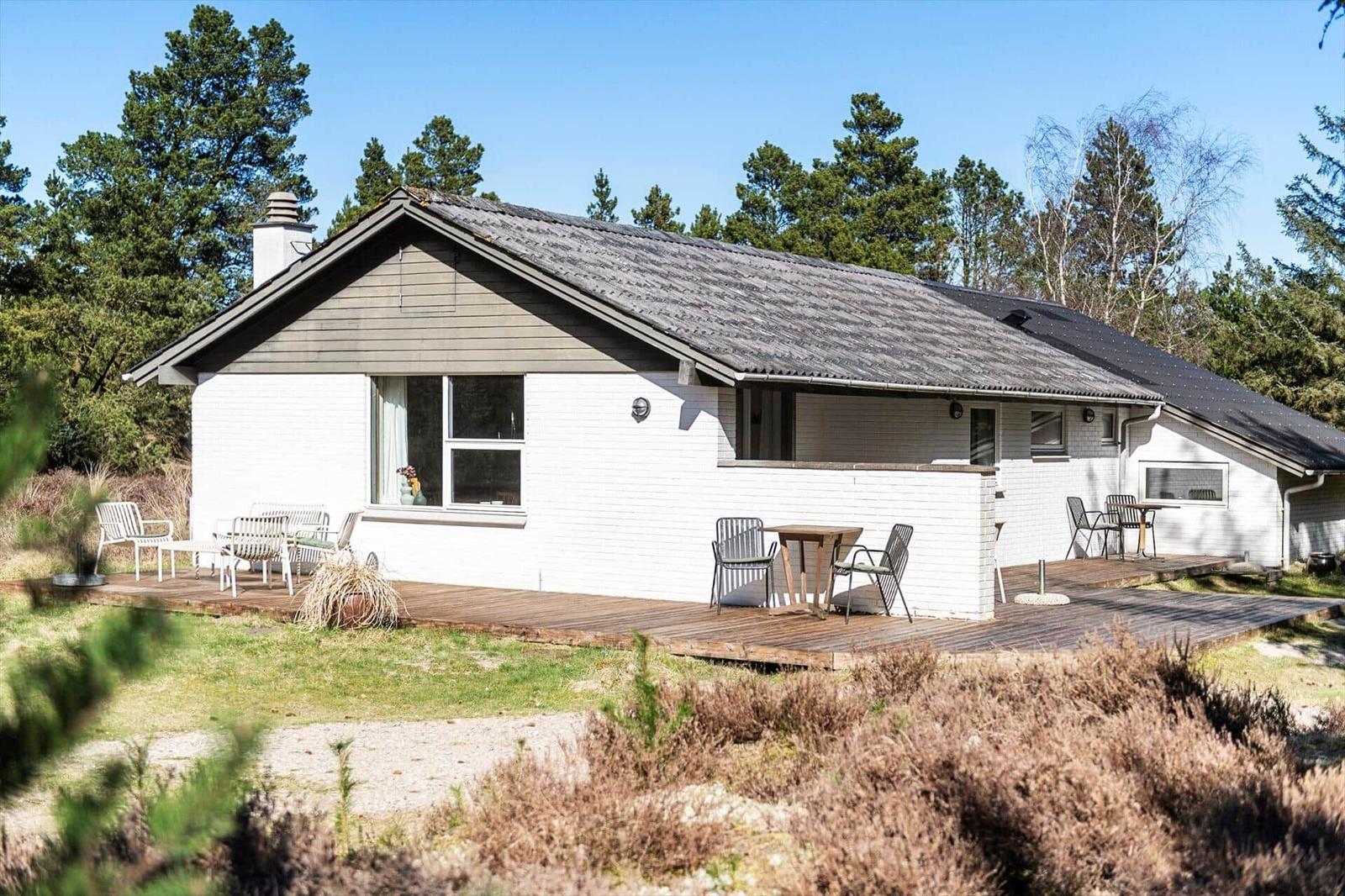 Wohnhaus mit Holzterrasse und Garten. Umgeben von Bäumen und Sträuchern.