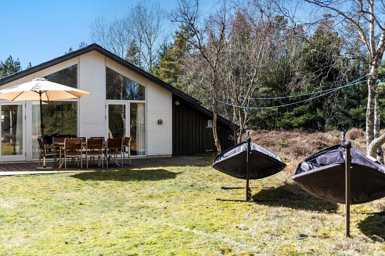 Moderne Ferienhaus mit Terrasse, Garten und Gartenmöbeln. Hintergrund: Wald.