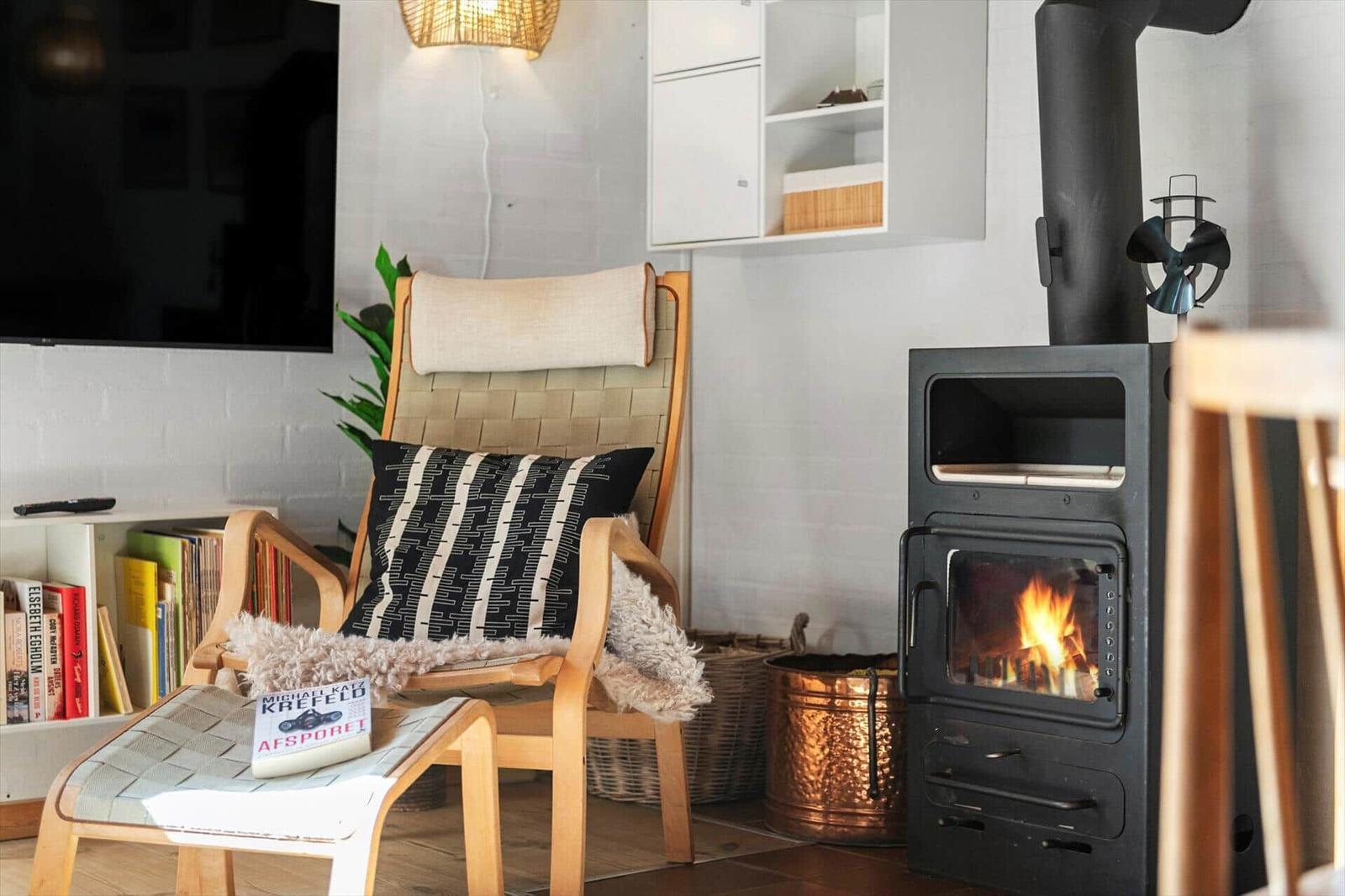 Ein Raum mit einem Sessel, Kamin und Fernseher an der Wand.