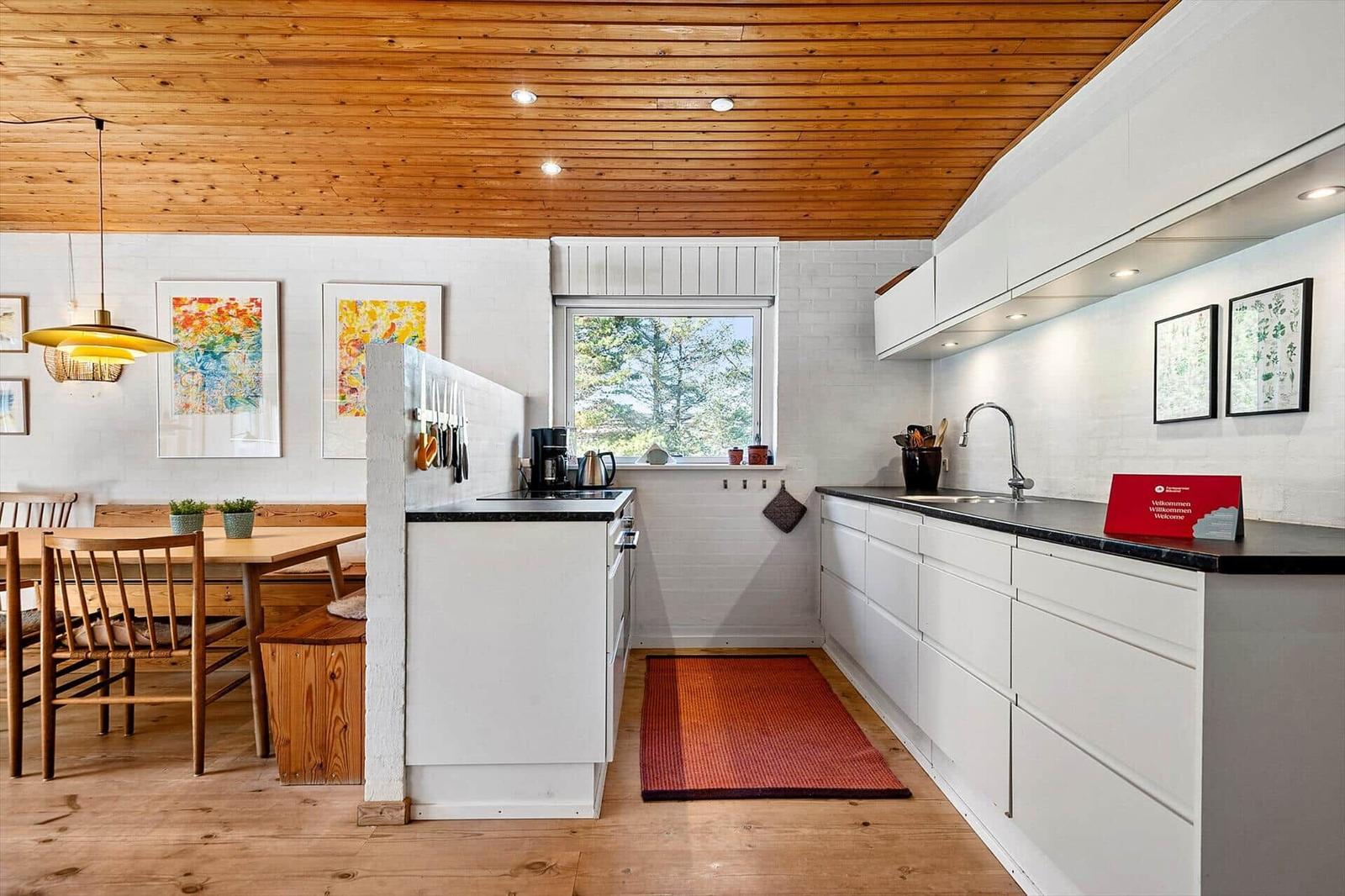 Küche mit Essbereich, Holzdecke und Fenster zum Garten