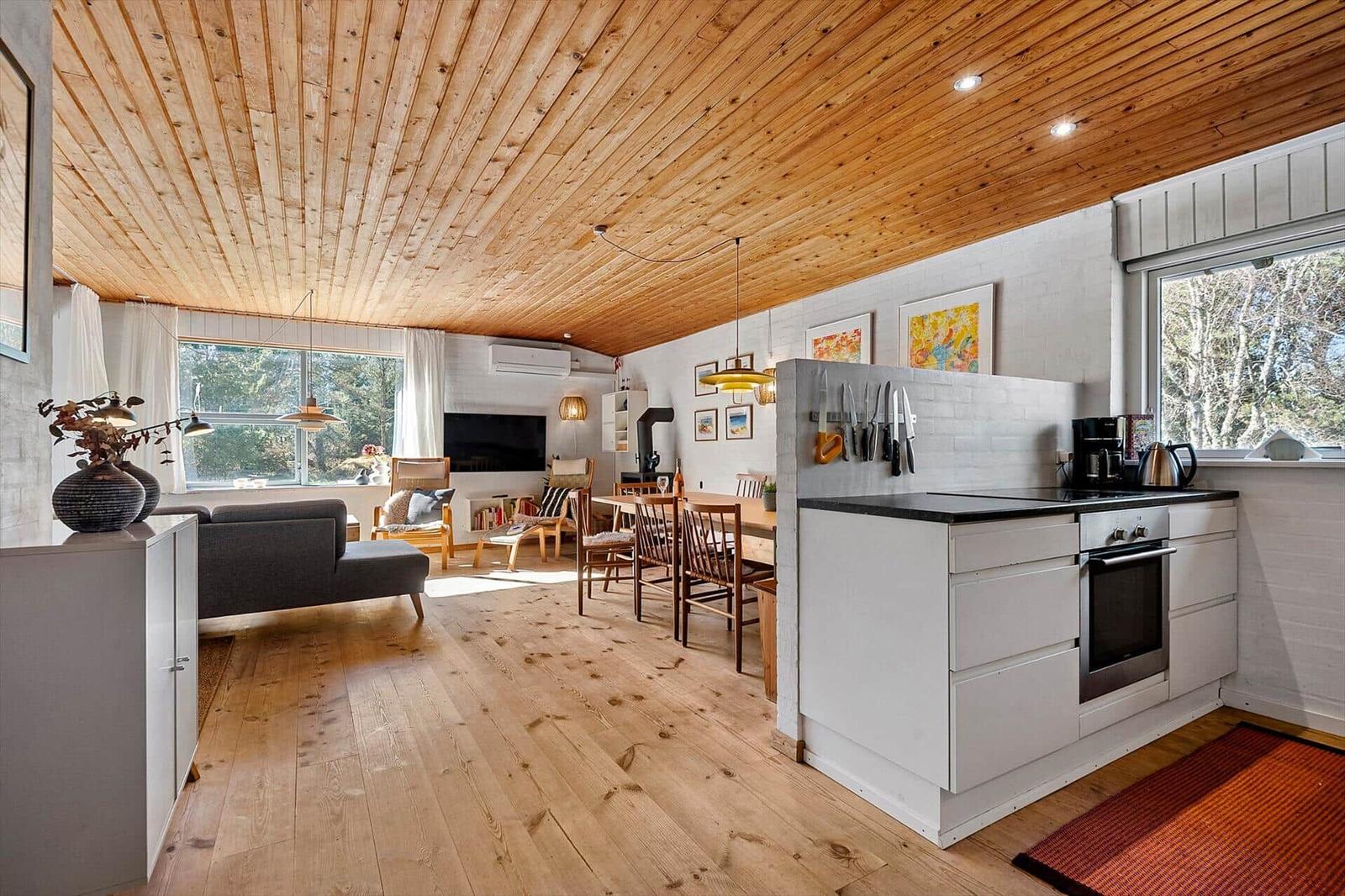 Küche mit Essbereich und Wohnzimmer unter Holzdecke.