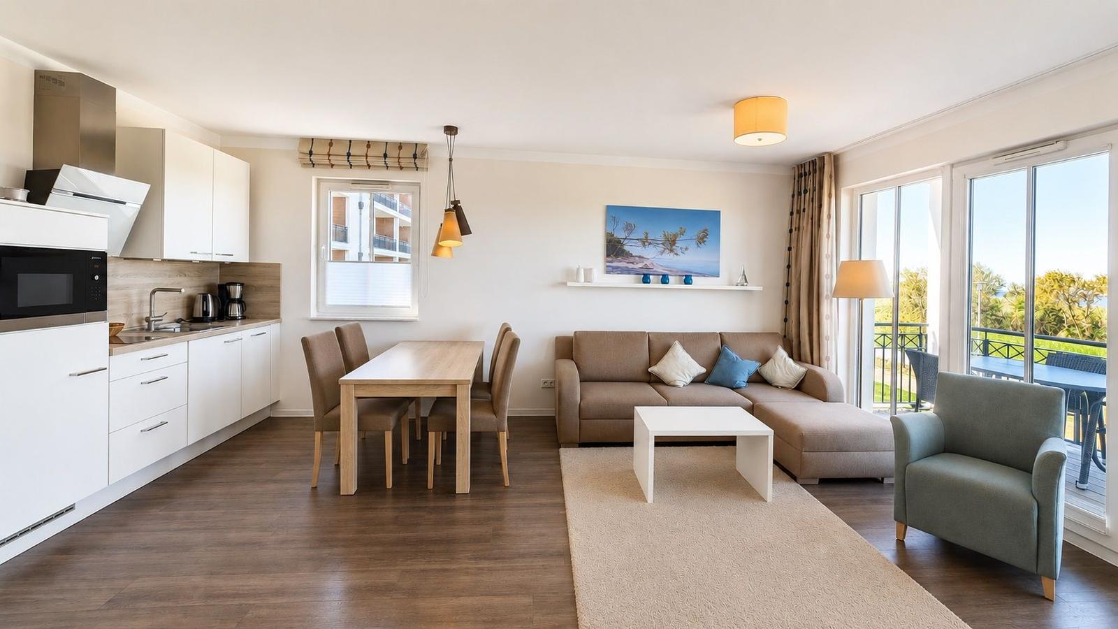 Wohnzimmer mit Sofa, Sessel und Balkonblick