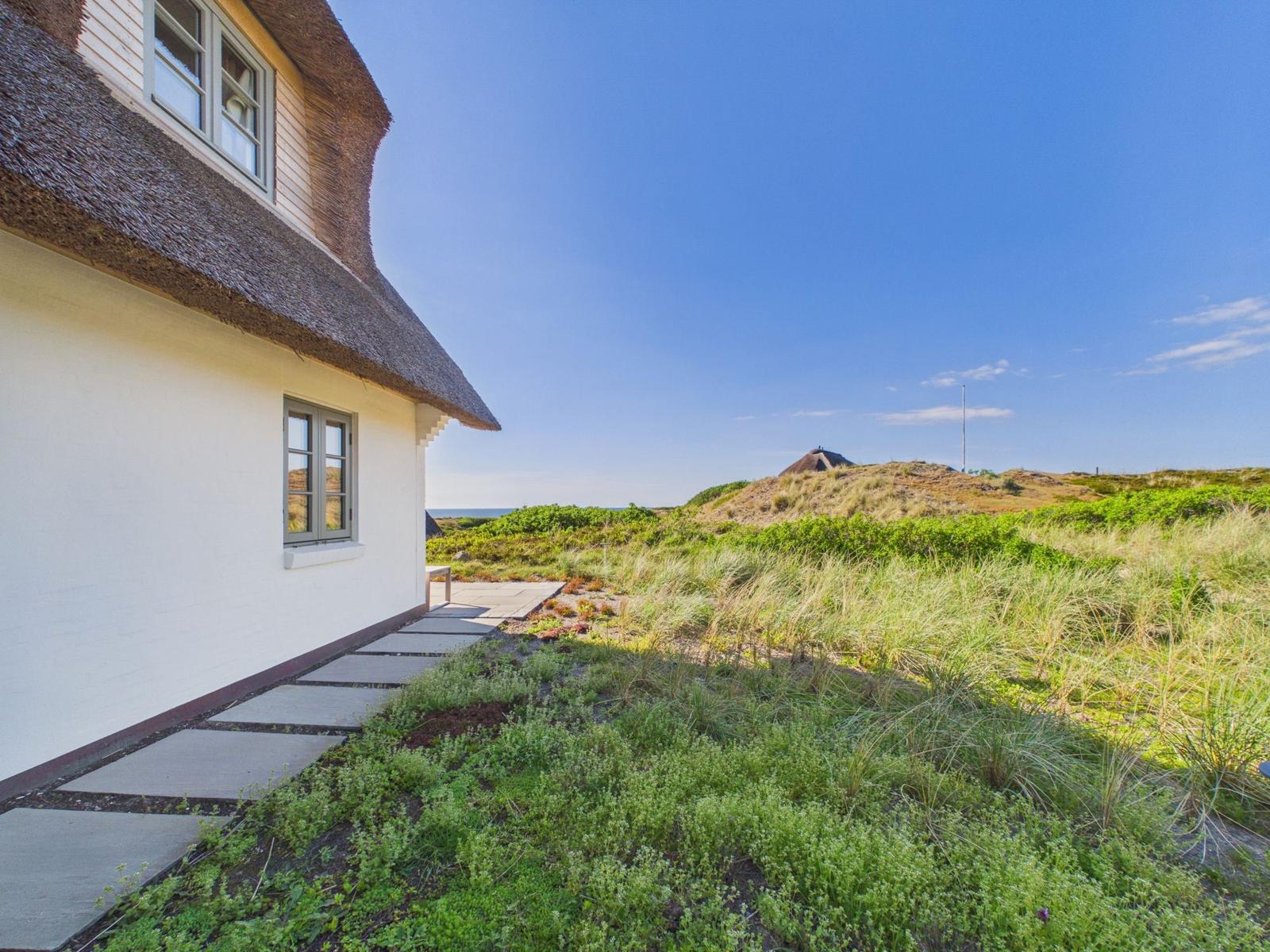 Haus mit Strohdach und Steinweg durch Grünflächen