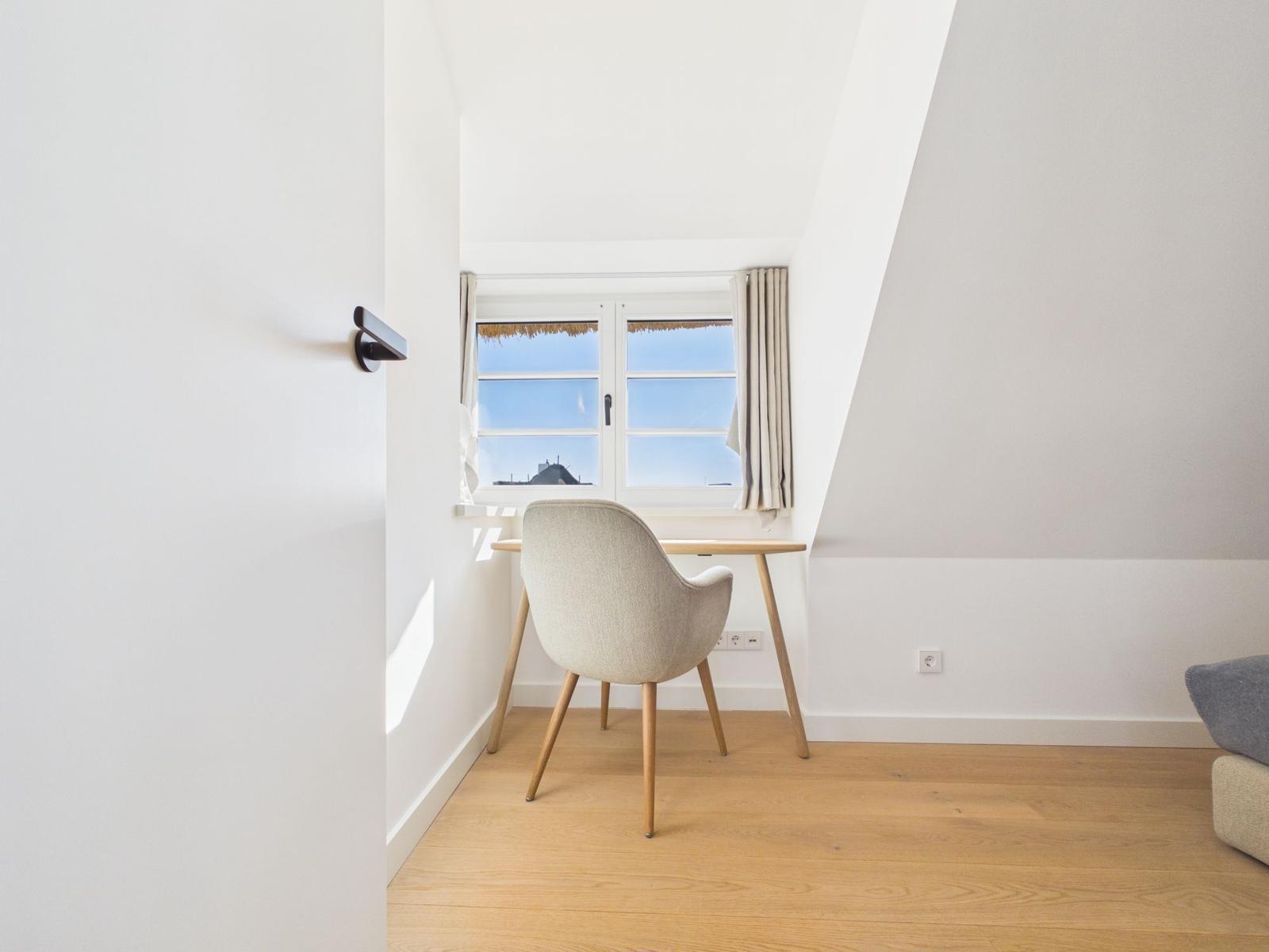 Schreibtisch mit Stuhl unter Fenster in Dachschrägenraum