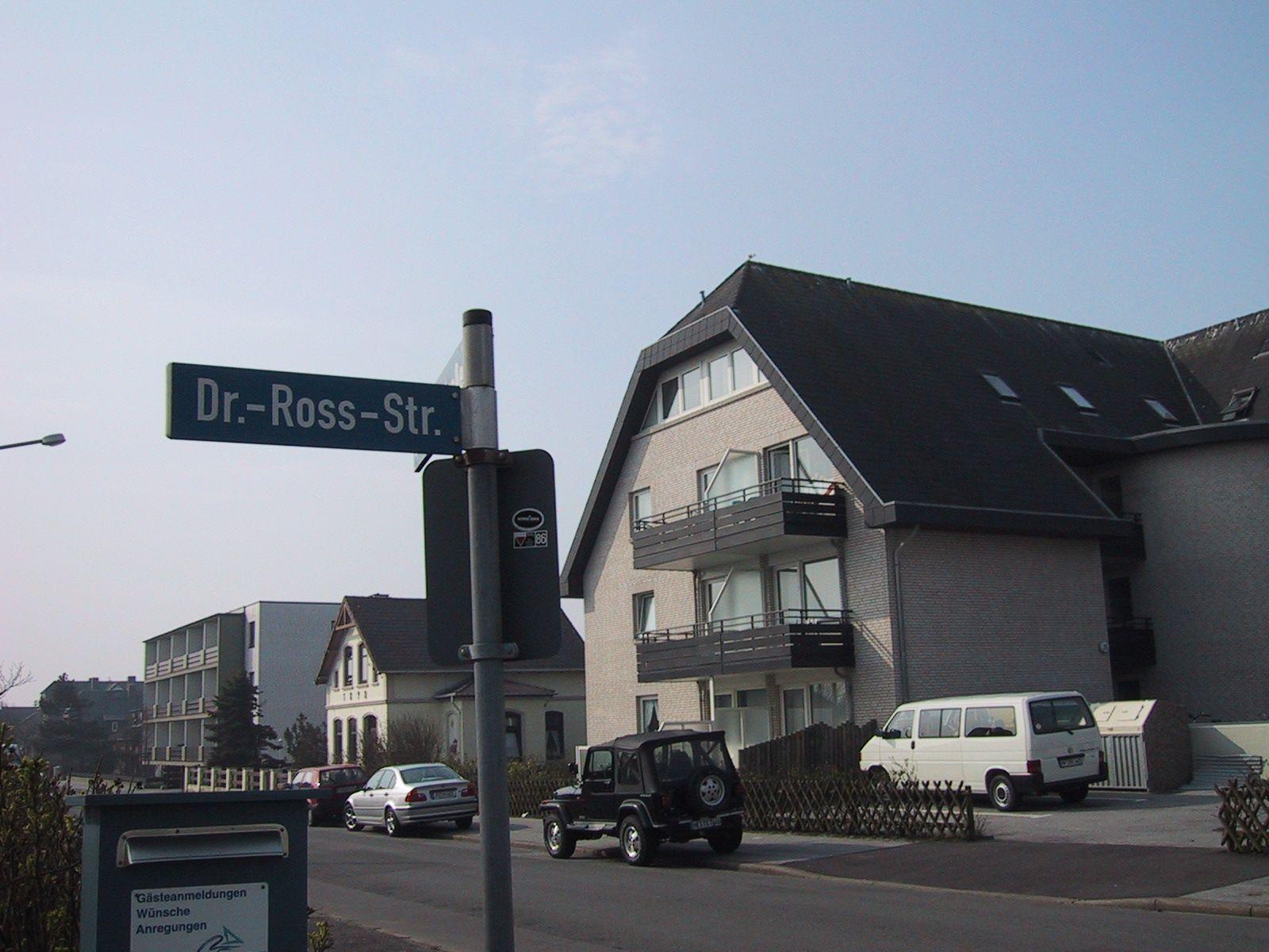 House with balconies on Dr.-Ross-Str. Parking spaces and street sign visible.