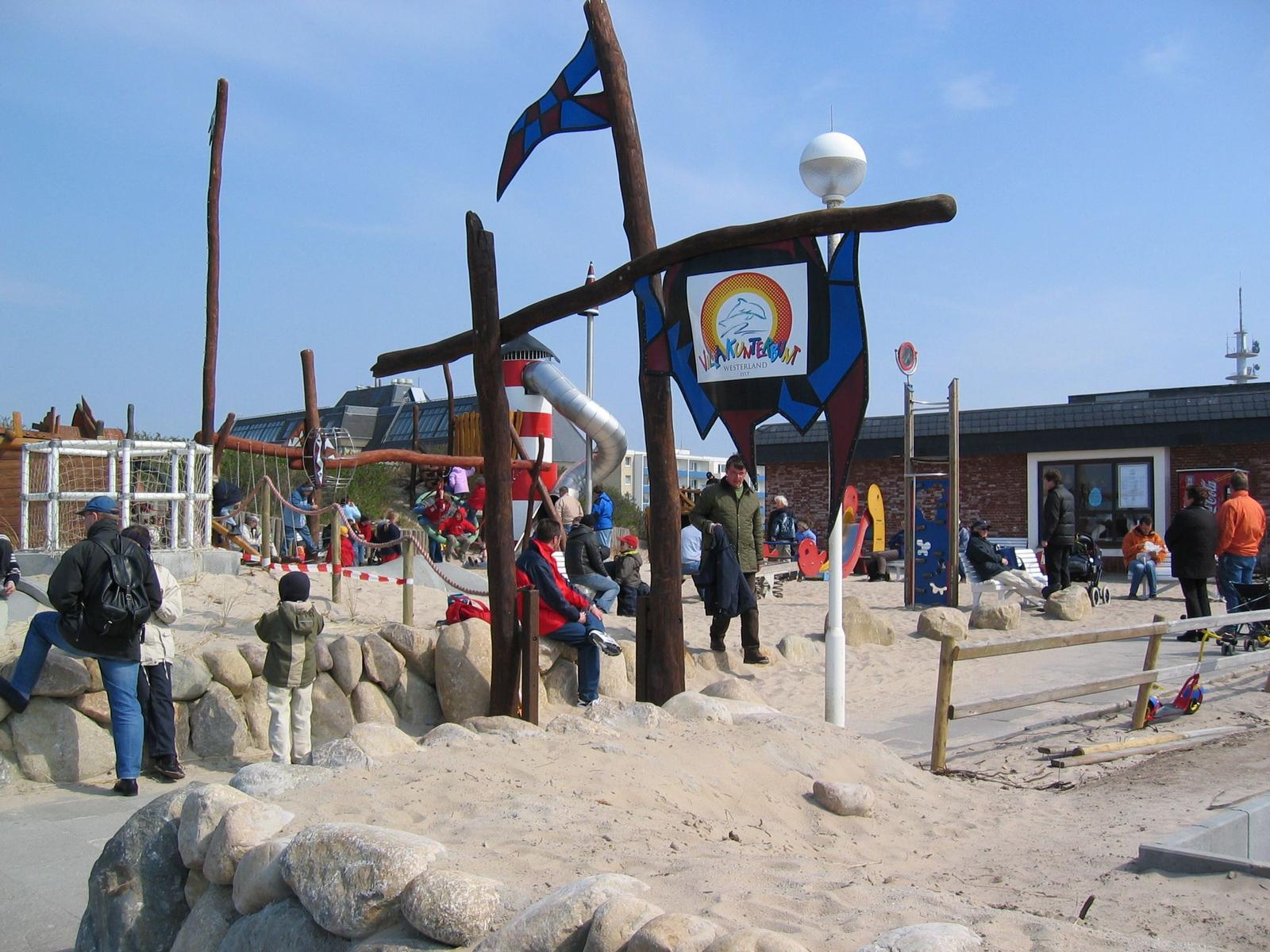Outdoor playground with sand, stones, and slide for children.