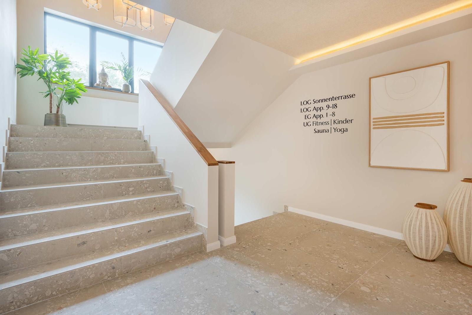 Hausflur mit Treppe, Wandtafel und Kunstwerk. Boden und Stufen aus Terrazzo.