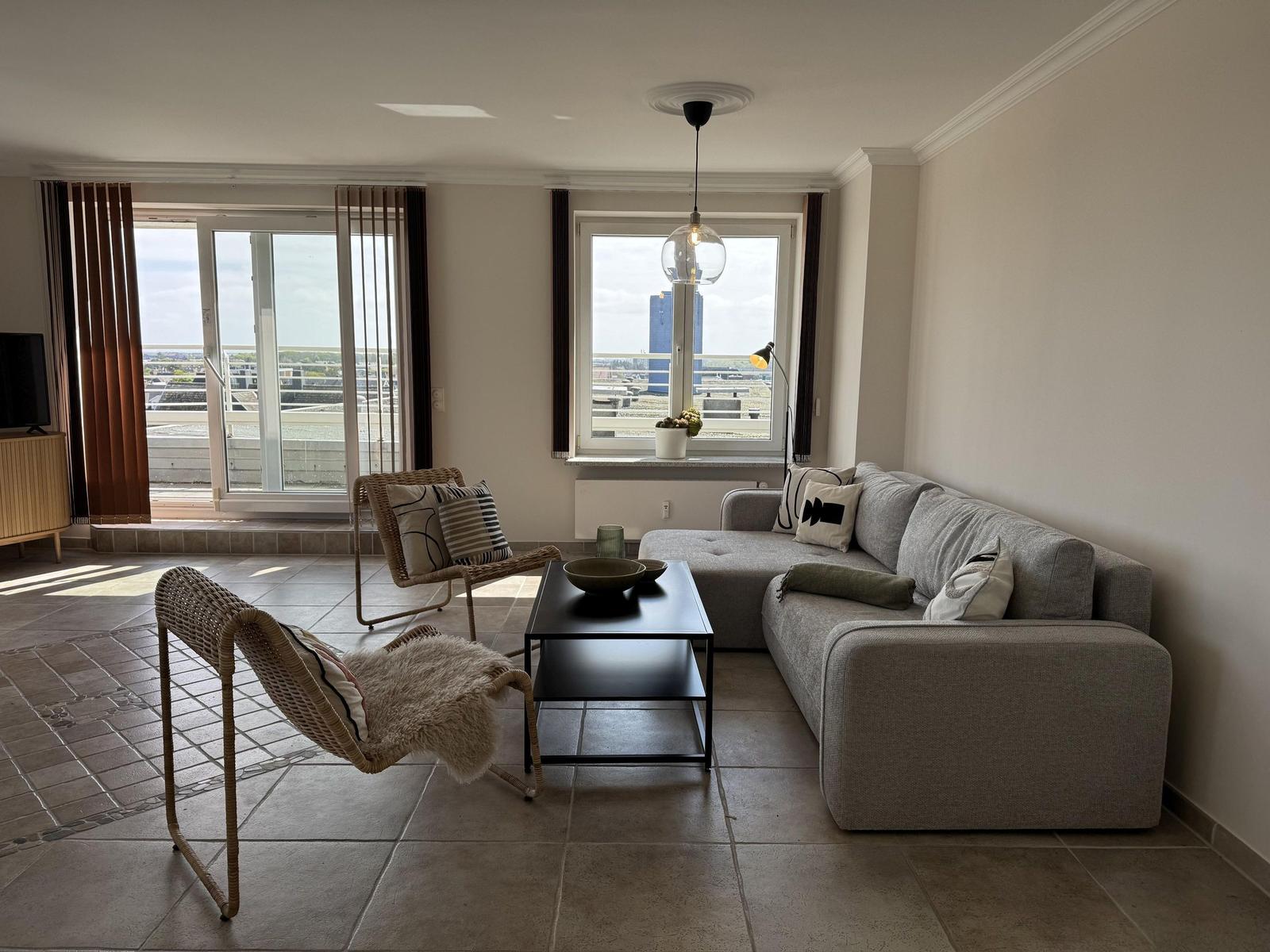 Living room with sofa, two chairs, and balcony view