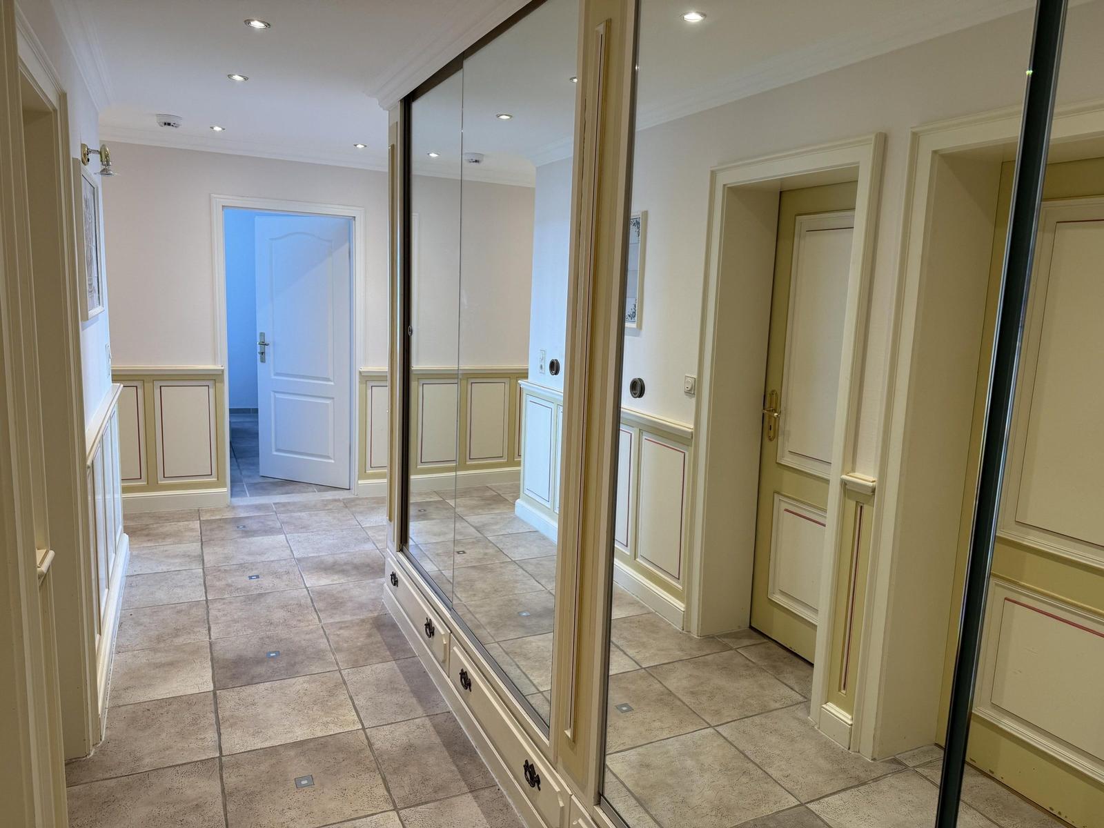 Hallway with mirrored closet, light walls, and tiled floor.