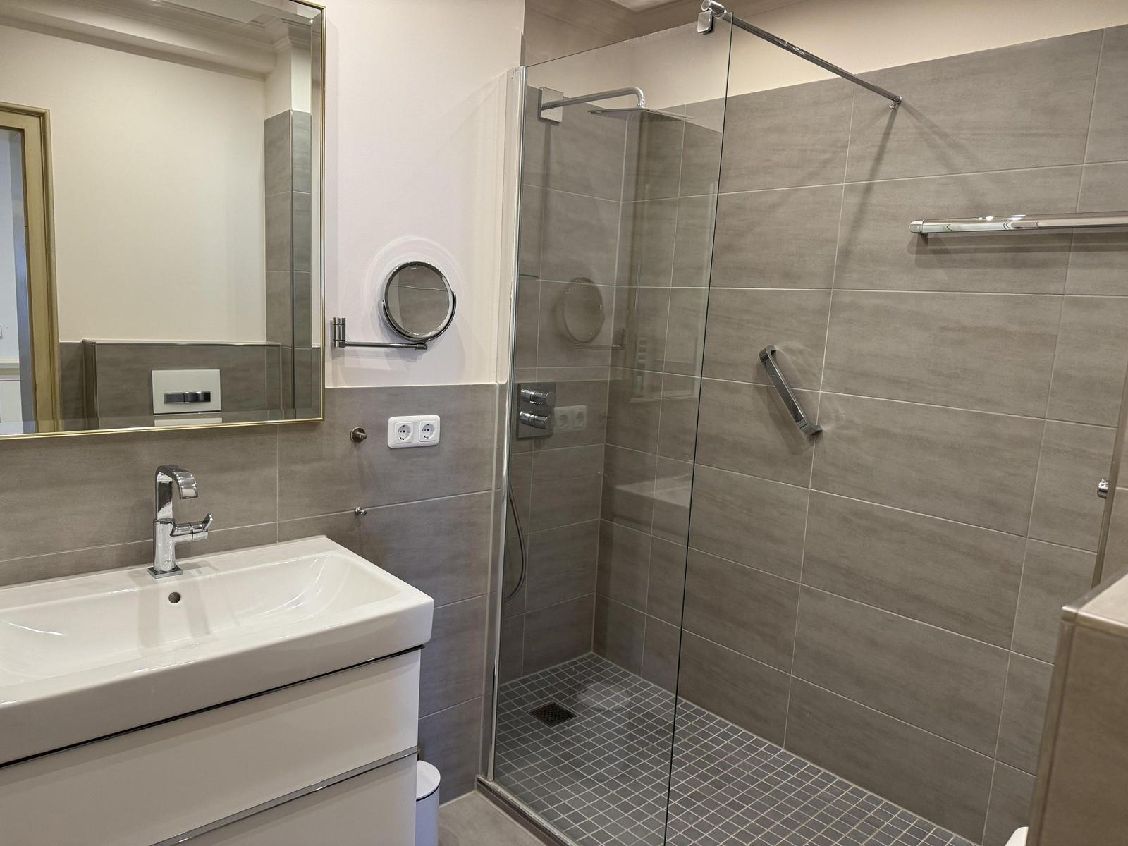 Bathroom with shower, sink, and mirror.