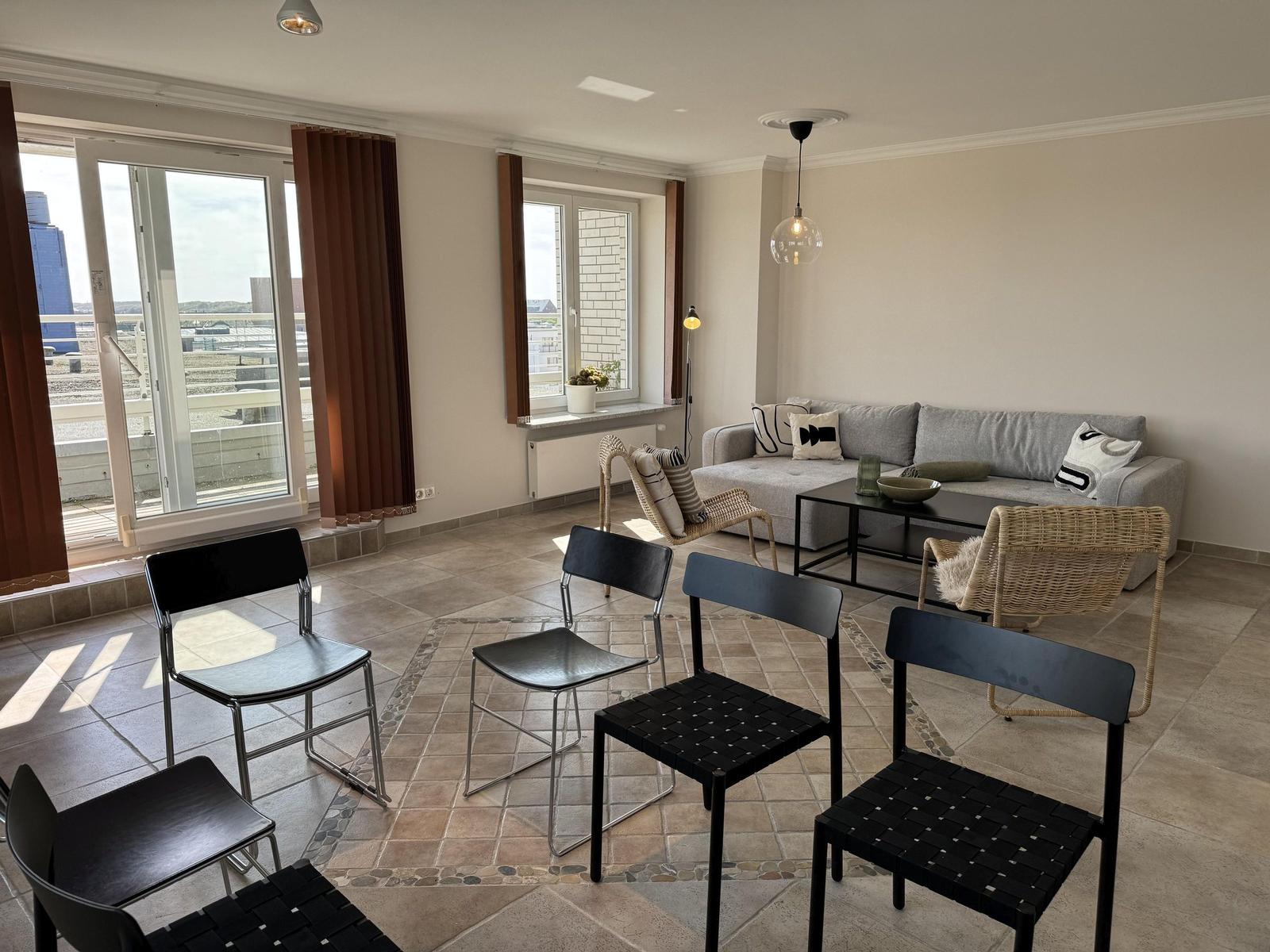Living room with sofa, chairs, and view of balcony.