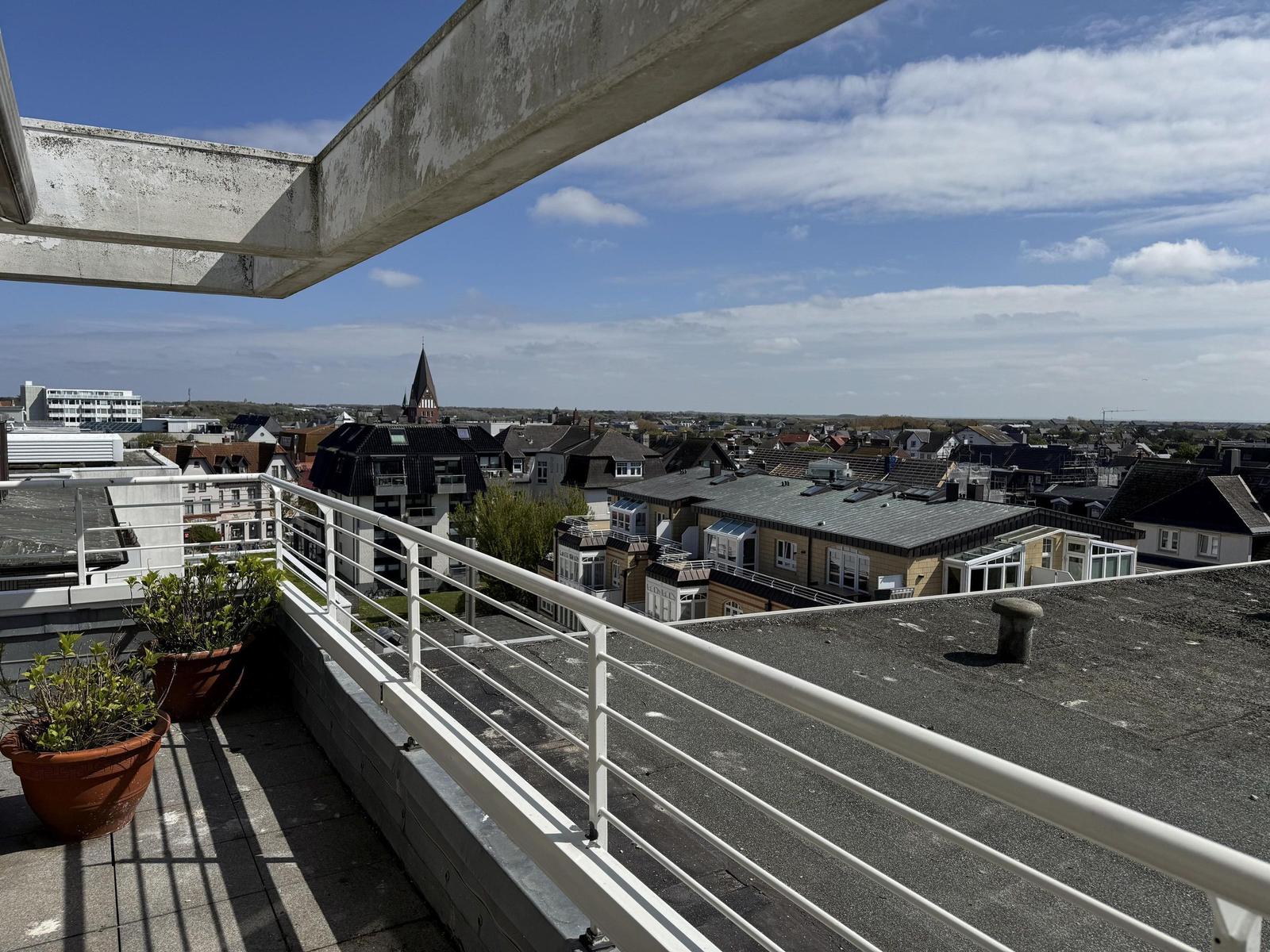 Terrace with view of town and church under blue sky.
