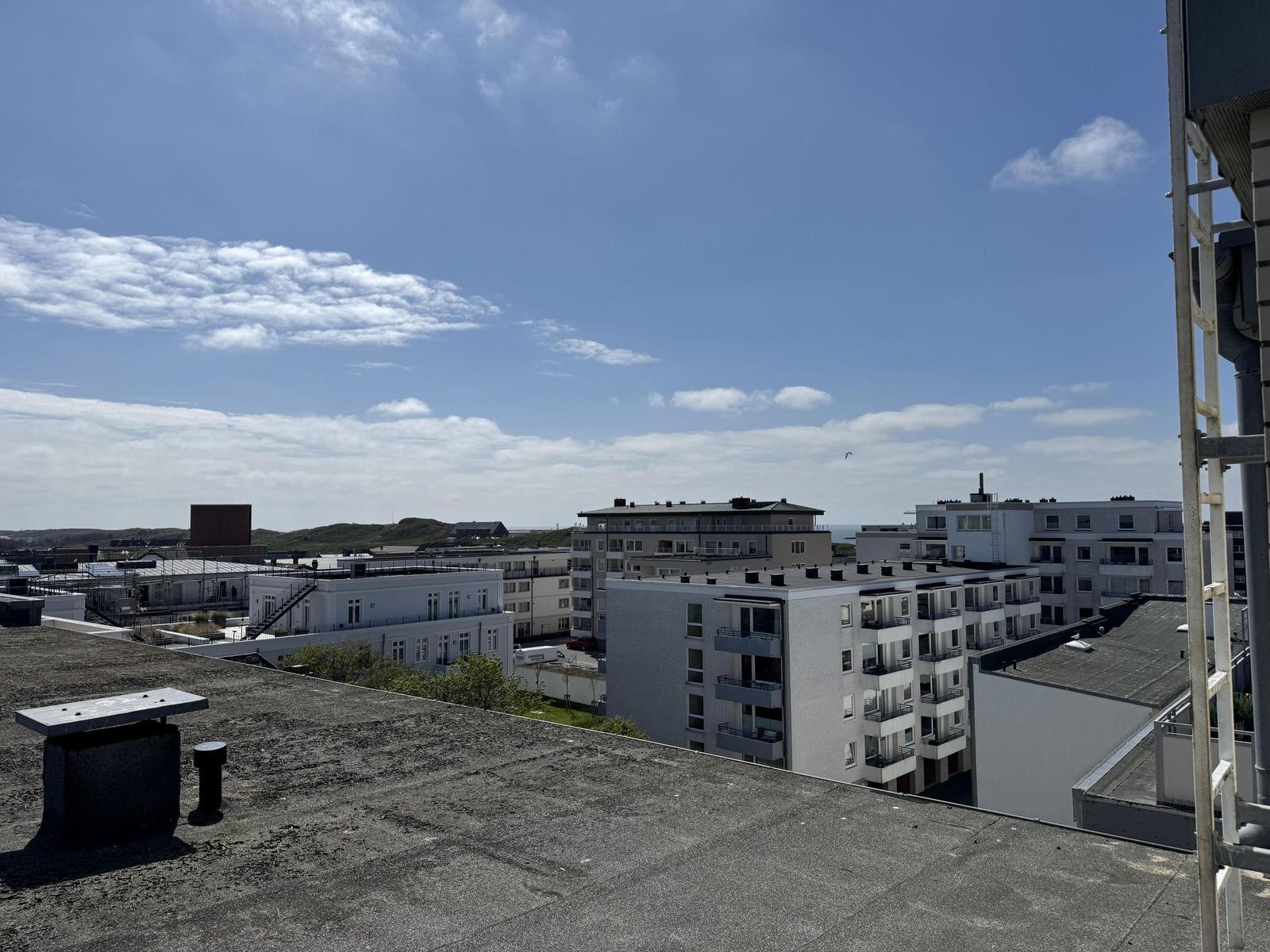 Roof top view over modern buildings and sky with white clouds.