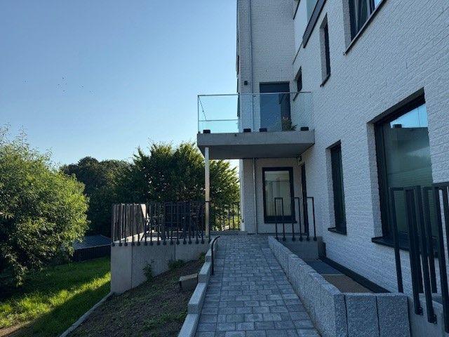 Haus mit Balkon, gepflasterter Weg und grüner Umgebung.