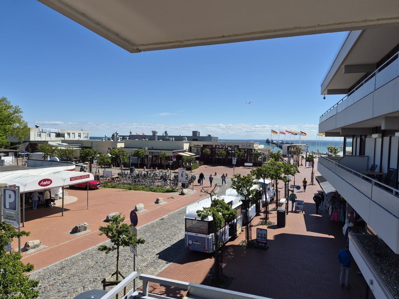 Blick auf belebten Strandpromenade mit Geschäften und Fahrrädern.