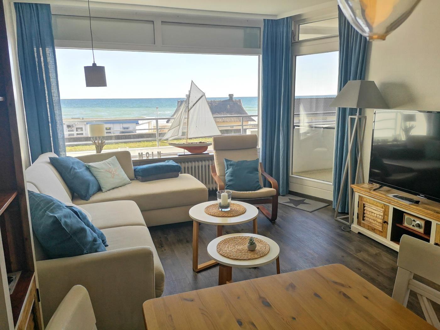 Wohnzimmer mit Blick aufs Meer, Sofa, Sessel und TV.