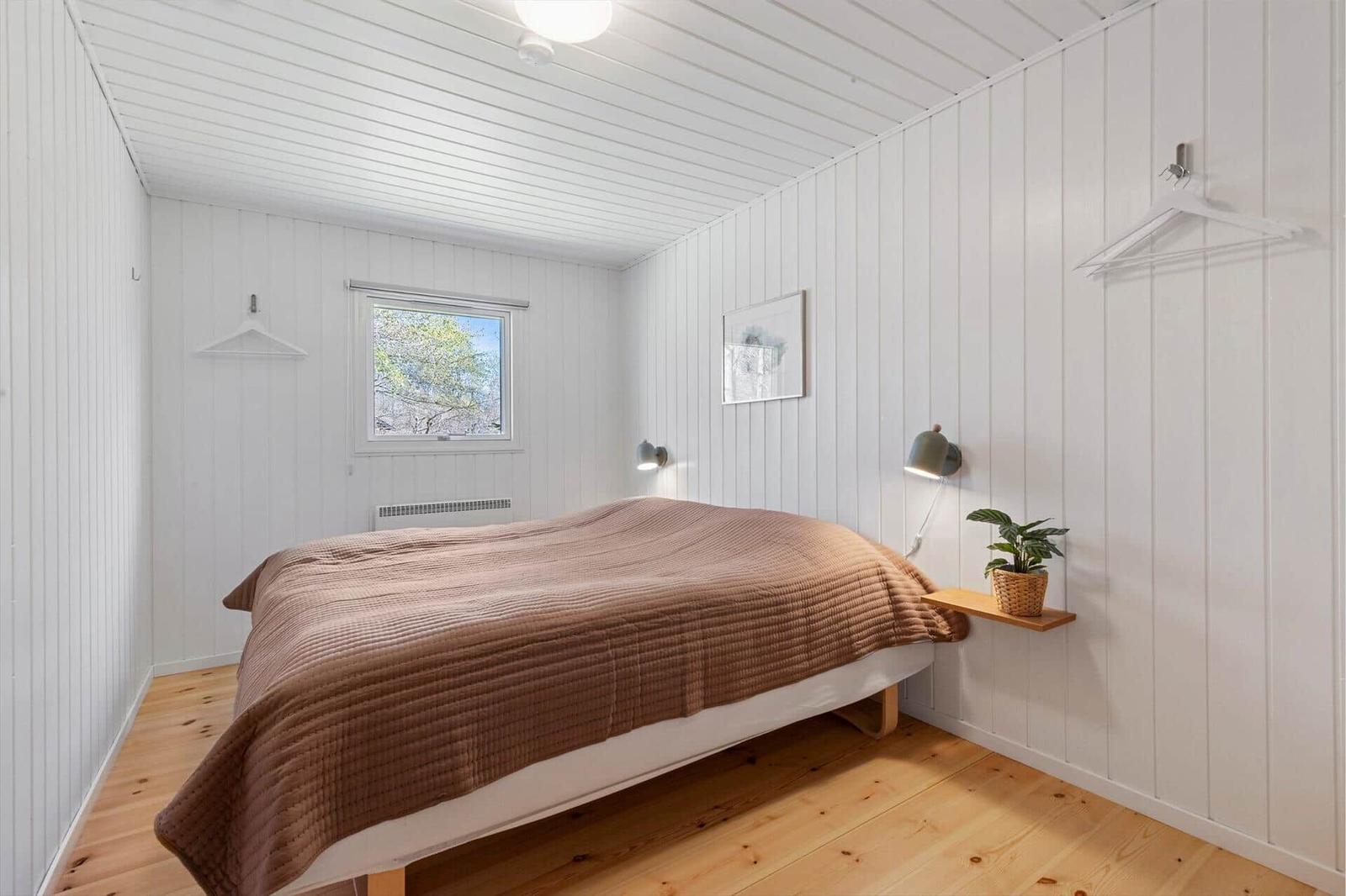 Bedroom with bed, window, and wooden floor.