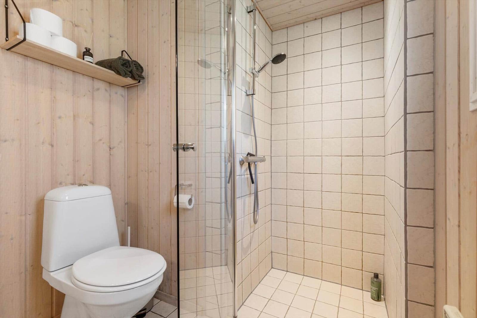 Bathroom with shower, toilet, and wooden wall cladding.