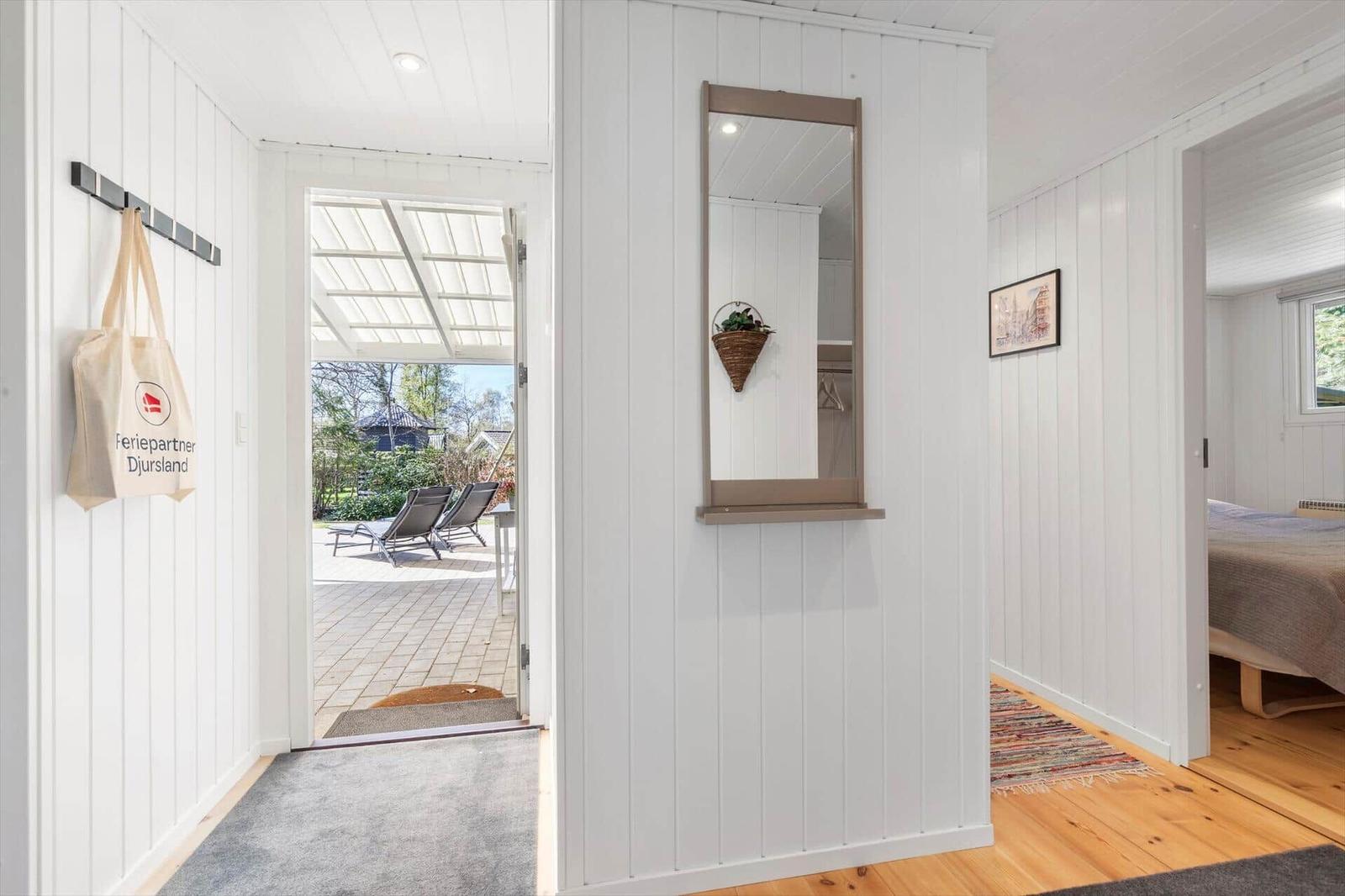 House with entryway, mirror, and view of terrace with lounge chairs.