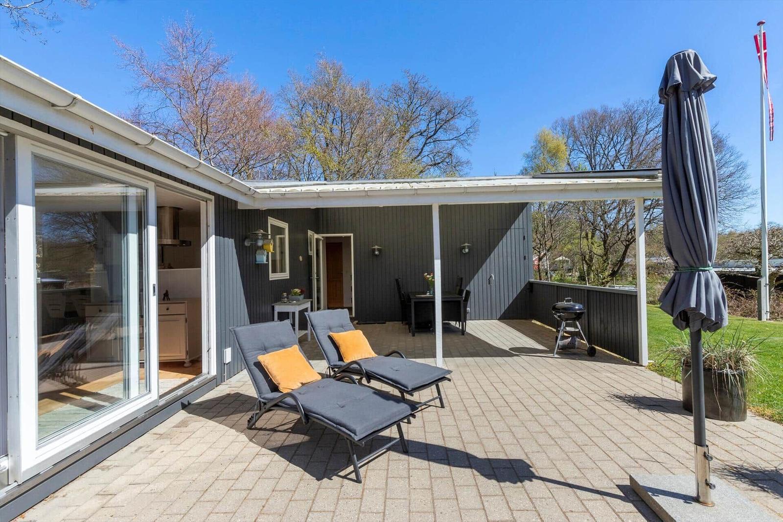 Deck with lounge chairs, grill, and umbrella. View into living area and garden.